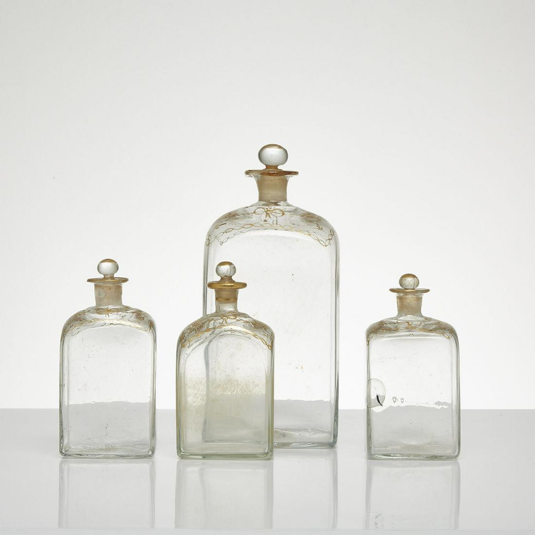 Quatre flacons couverts à quatre pans ornés de filets or. Four covered flasks with four: Quatre flacons couverts à quatre pans ornés de filets or.Four covered flasks with four sides decorated with gold filets.H 23 à H 13 cm - H 9 to H 5 1/8 in.