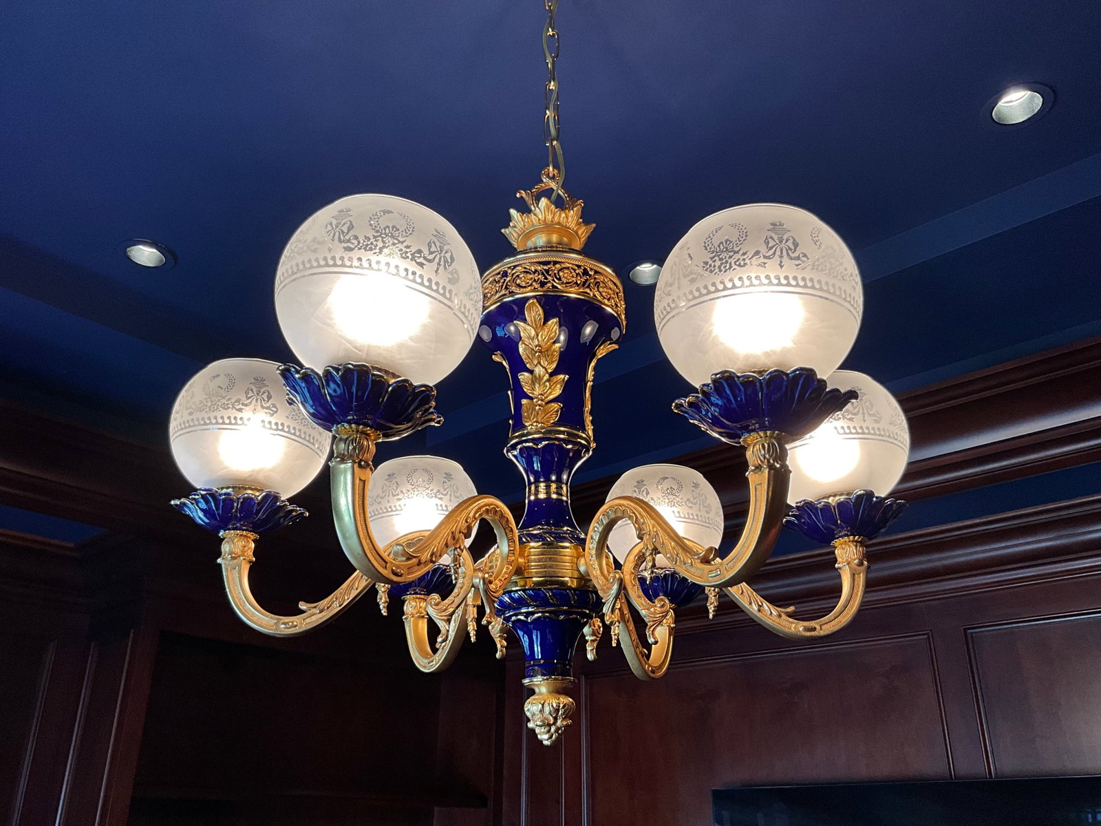 French Empire Style Gilt Brass Cobalt Blue Porcelain Chandelier: French empire style gilt laurel leaf accents on cobalt blue porcelain frosted round shades on each of the 6 arms measuring approximately 31" diameter x 40" high