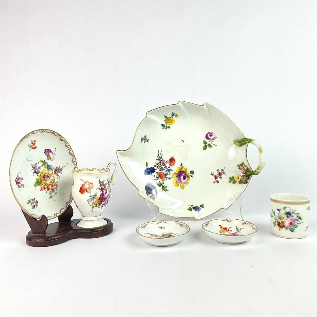 Meissen Dishes: Includes leaf plate, demitasse bowls, one cup, and matching saucer and tea cup with wood base. Leaf plate: 10" long x 8.5" high. Tallest cup: 3.5" high