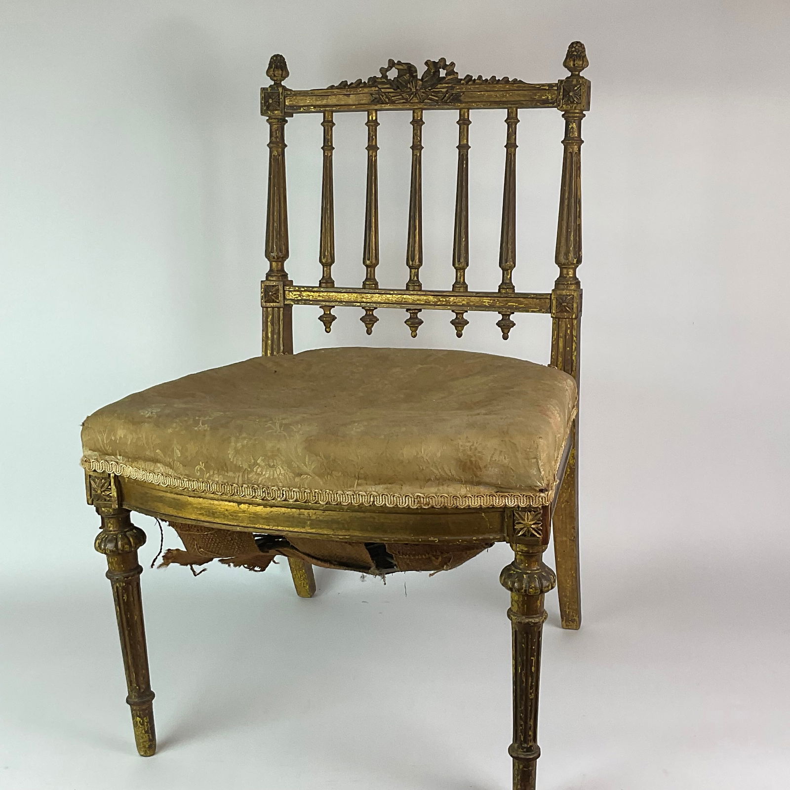 Antique French Gilt Upholstered Slipper Chair: Original upholstery, gilt, springs. Missing top loop above the ribbon. Springs are falling out from bottom. Measurements 18”wide x 16”depth x 28.5”high and seat height is 14.5”