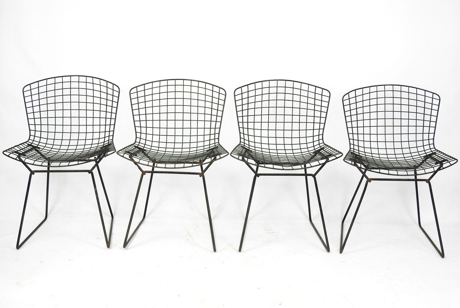 BERTOIA: Harry BERTOIA (1915-1978) Quatre chaises "Wire DK" en fil d'acier noirci. Avec galettes anciennes en cuir. Edition ancienne. 76 x 53 x 47 cm (usures)