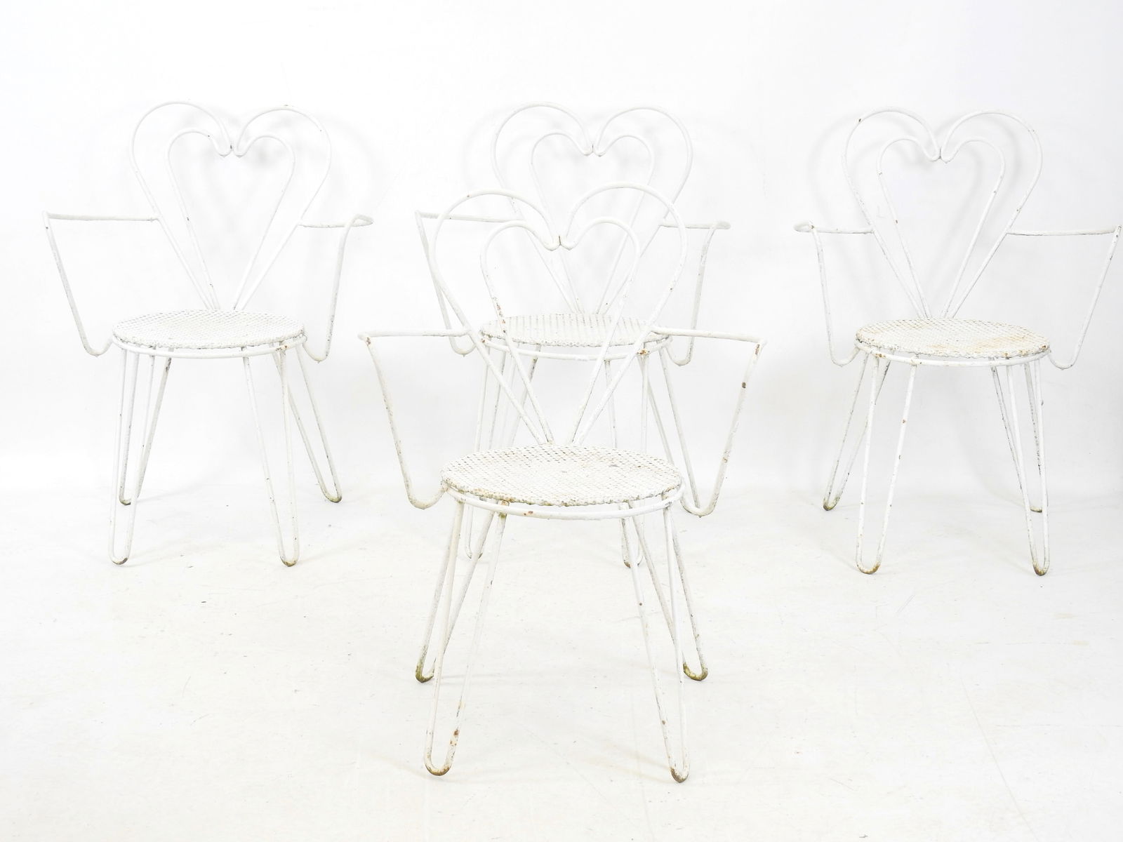 Attribue a Mathieu MATEGOT (1910-2001): Quatre fauteuils de jardin en fil de fer relaque blanc, sur: Attribue a Mathieu MATEGOT (1910-2001): Quatre fauteuils de jardin en fil de fer relaque blanc, sur tôle perforee trefle, a dossiers coeurs, H 80 - L 58 cm Usures.