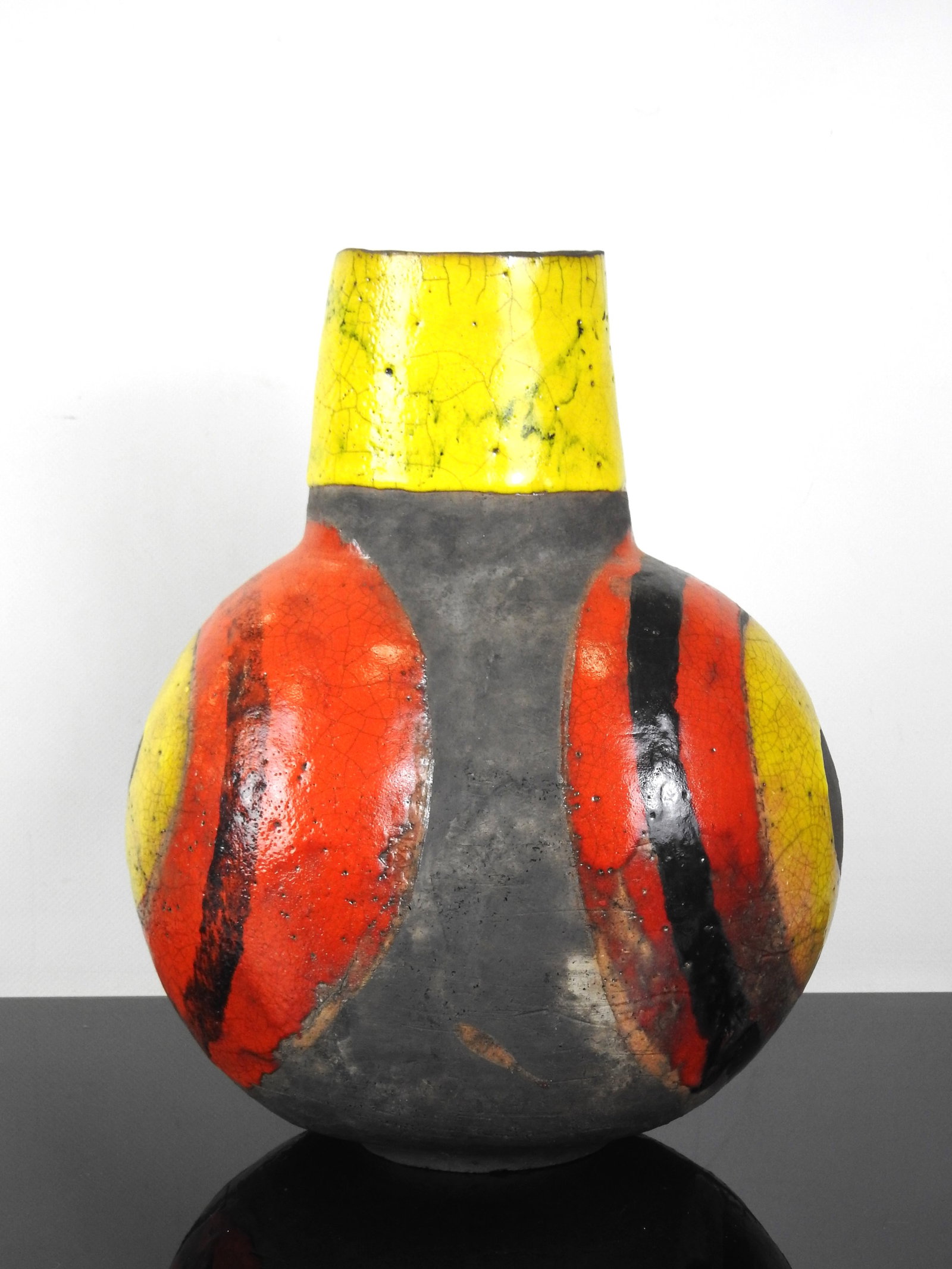IMPORTANT VASE en terre partiellement emaille a de: IMPORTANT VASE en terre partiellement emaille a decor de cercles jaune, rouge, noir. Signature Reboul.H 35 - L: 26 cm