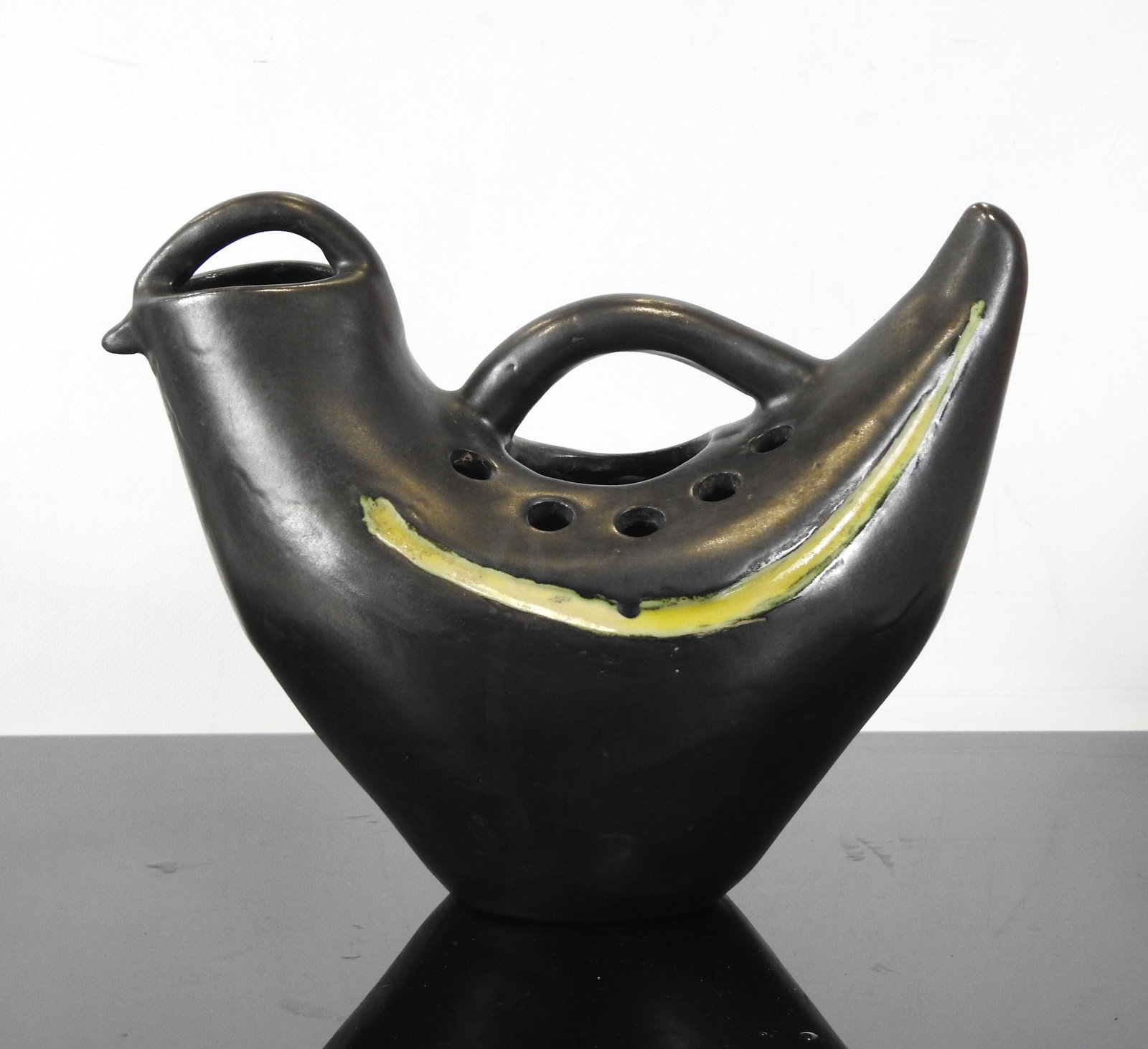 MADO JOLAIN (1921-2019) : Vase cocote en ceramiqu: MADO JOLAIN (1921-2019) : Vase cocote en ceramique noire ornee de deux bandes jaunes, avec anse, bec et trous pour les fleurs. Non signe. Circa 1950. H: 25 - L : 30 cm