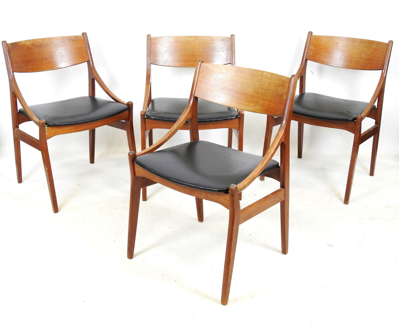 QUATRE CHAISES en teck et assise en skaï noir repo: QUATRE CHAISES en teck et assise en skaï noir reposant sur quatre pieds fuseles. Travail Danois - Estampille sous l assise. H.74 - L.47,5- P.42 cm. Usures et petits accidents.