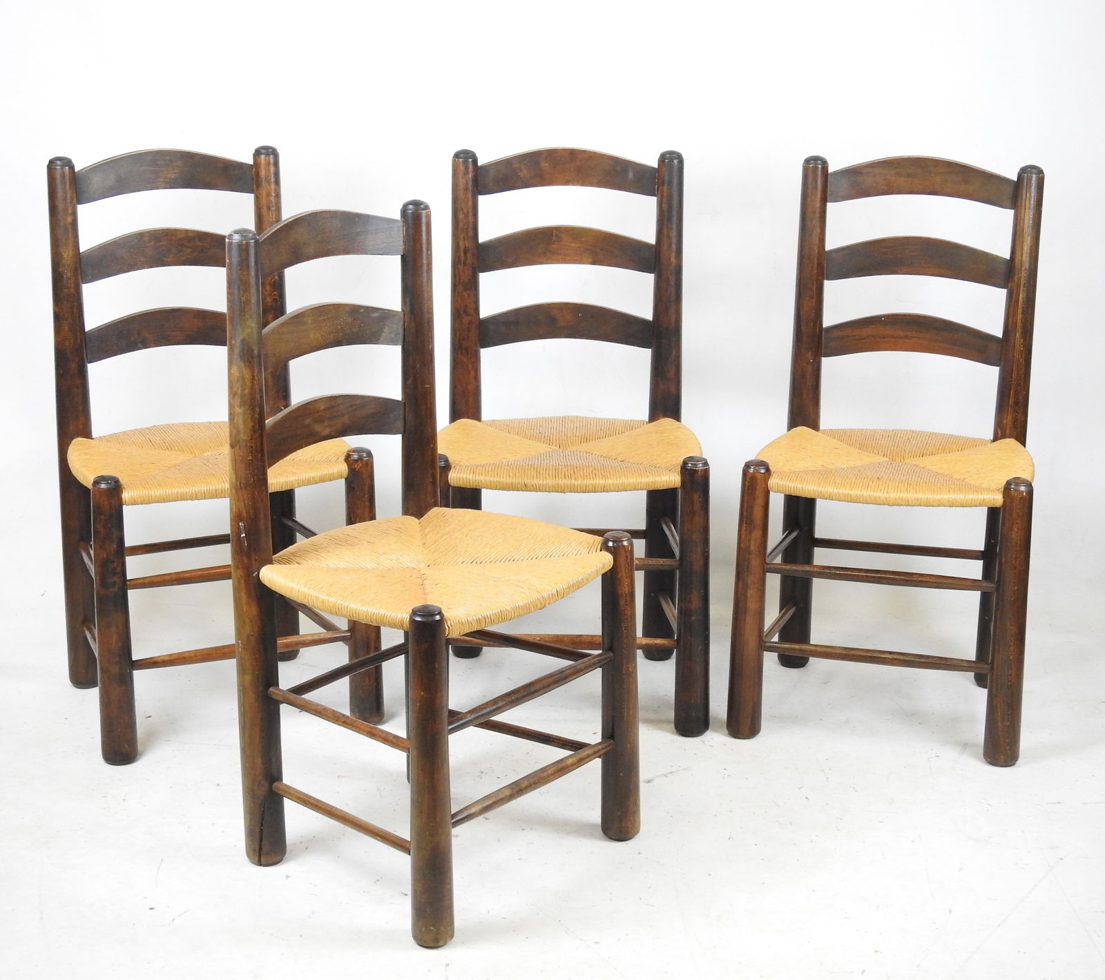 Georges ROBERT (XXeme), attribue a : Quatre chaise: Georges ROBERT (XXeme), attribue a : Quatre chaises en bois teinte et assises paillees. Travail des annees 1950. H. 90 - L. 45 - P. 39 cm. Fente a un pied.