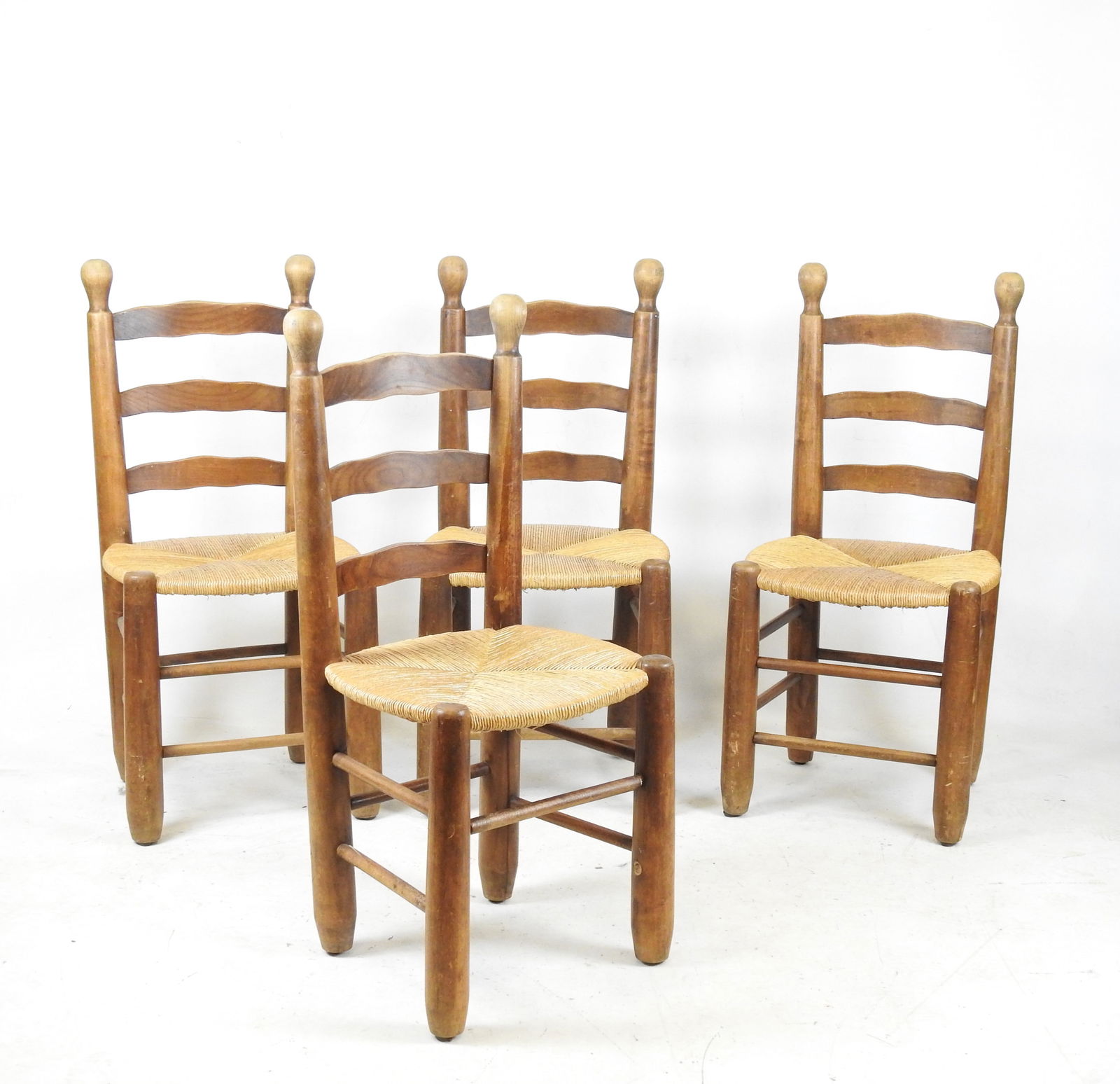 Georges ROBERT (XXeme), attribue a : Quatre chaise: Georges ROBERT (XXeme), attribue a : Quatre chaises en bois naturel et assises paillees. Travail des annees 1950. H. 97 - L. 45 - P. 40 cm. Manque une entretoise, legeres fente a un dossier, usures d