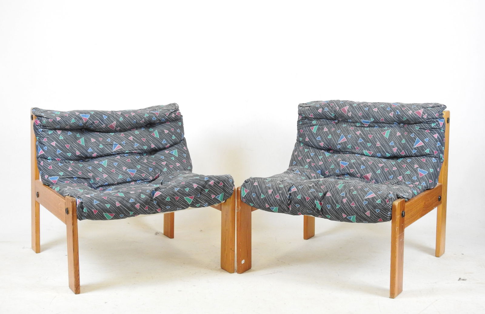 PAIRE DE CHAUFFEUSES en pin, assise garni d un tis: PAIRE DE CHAUFFEUSES en pin, assise garni d un tissu bleu a motifs geometriques polychromes. Annees 1980. H. 60 - L. 70 - P. 61.5 cm. Usures au tissu, quelques rayures d usage.