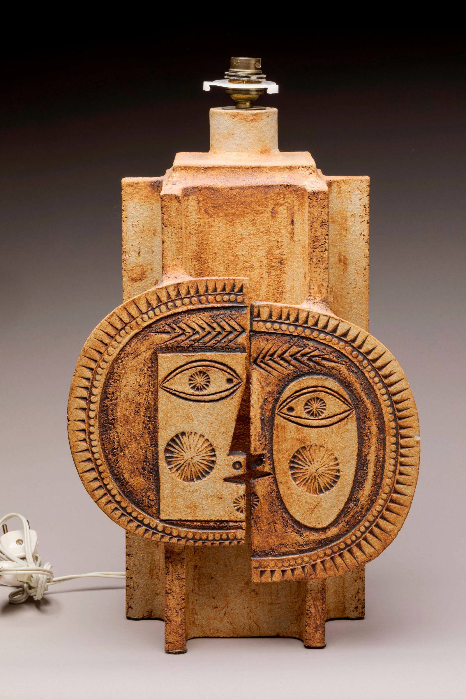 Roger CAPRON (1922-2006) Pied de lampe modele dit: Roger CAPRON (1922-2006) Pied de lampe modele dit "Le baiser" ou "Le jour et la nuit" en gres emaille brun a decor de deux profils, masculin et feminin, disposes en soleil.Signe au tampon en creux «