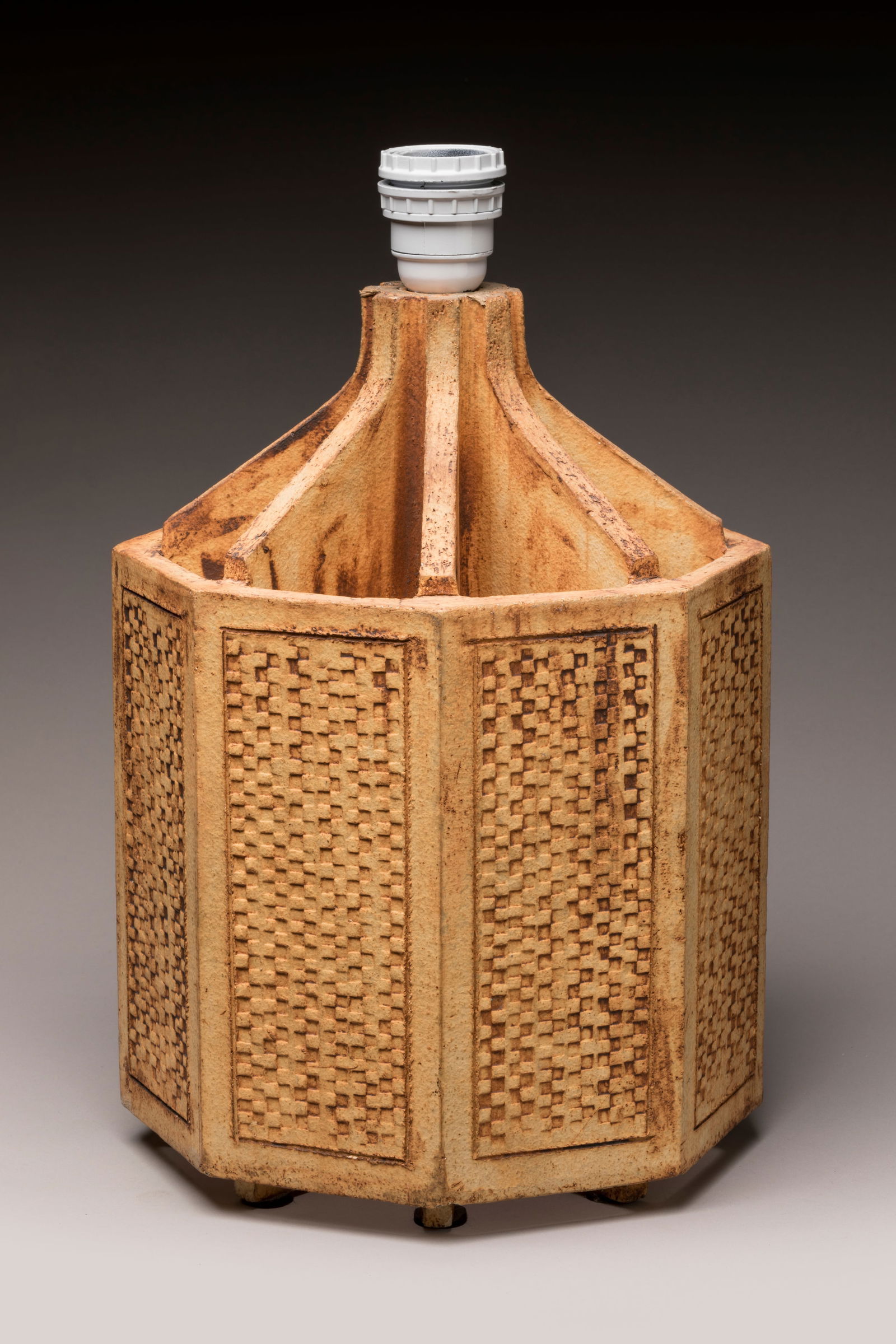 Roger CAPRON (1922-2006) Pied de lampe en gres em: Roger CAPRON (1922-2006) Pied de lampe en gres emaille brun de forme octogonal a pans coupes, decor façon vannerie.Signe au tampon en creux « Capron Vallauris France »electrifie. On y joint un abat