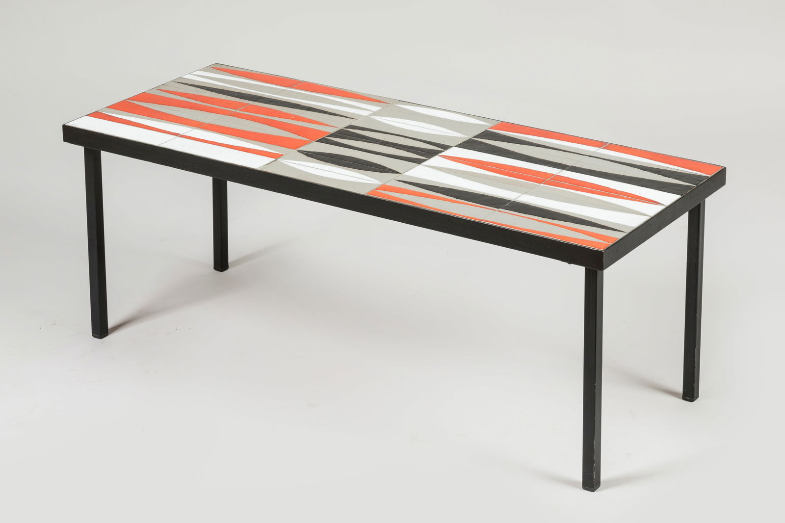 Roger CAPRON (1922-2006) Table basse de forme rect: Roger CAPRON (1922-2006)Table basse de forme rectangulaire modele "Navette" a carreaux de ceramique dans les tons orange, blanc et noir. Le pietement en metal laque noir, signee sur le plateau. Vers 1