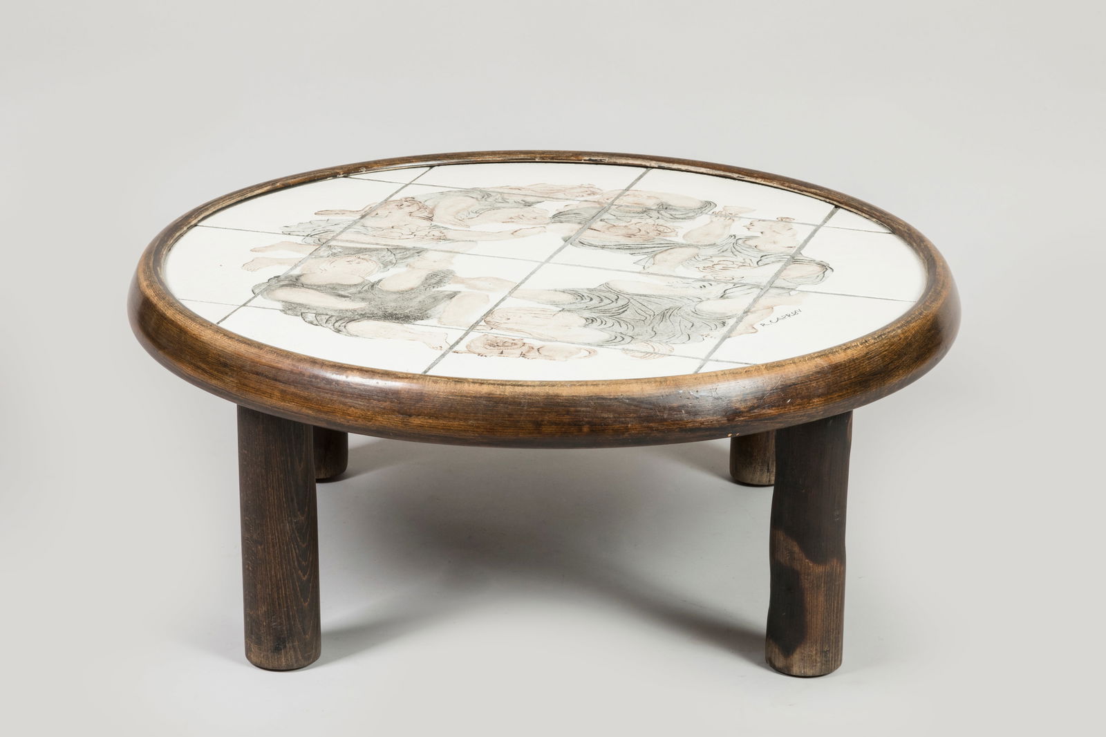 Roger CAPRON (1922-2006) Table basse de forme cir: Roger CAPRON (1922-2006) Table basse de forme circulaire reposant sur quatre pieds tubulaires en bois naturel, plateau compose de seize carreaux en faïence a decor circulaire d'une scene de vendange.
