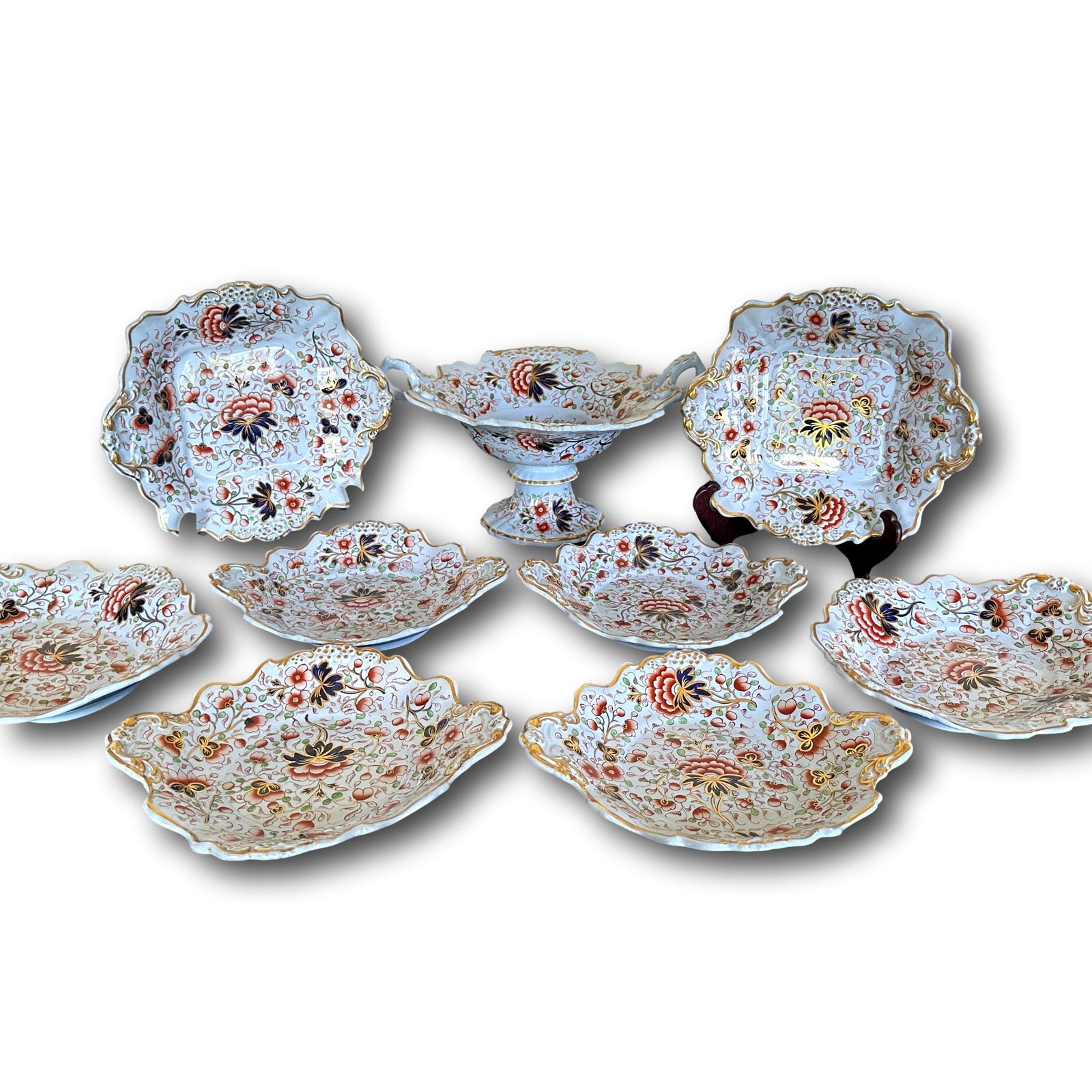Antique Imari Plate Set: Set includes 2 plates measuring 10 1/4" x 9 1/4", 2 oval plates measuring 11" x 9 1/4", 4 plates measuring 10" x 9". Slight hairline to one oval plate, repair to pedestal bowl and chip to handle. See 