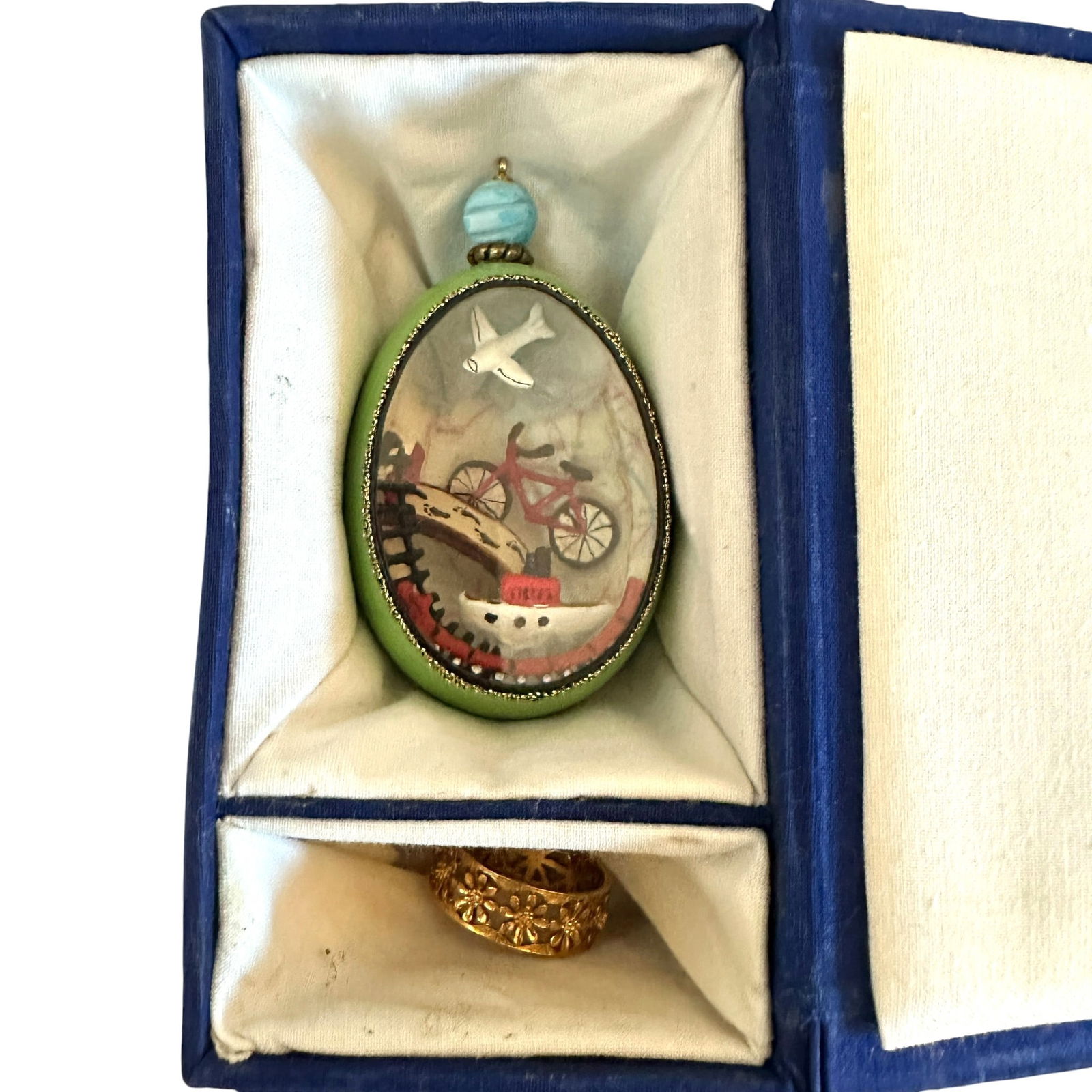 JBW Studios Collectible Decorative Egg Signed JBP: A hand-decorated enamel miniature egg featuring a whimsical three-dimensional interior vignette visible through an oval glass window. The exterior presents a pale green vitreous enamel ground with gil