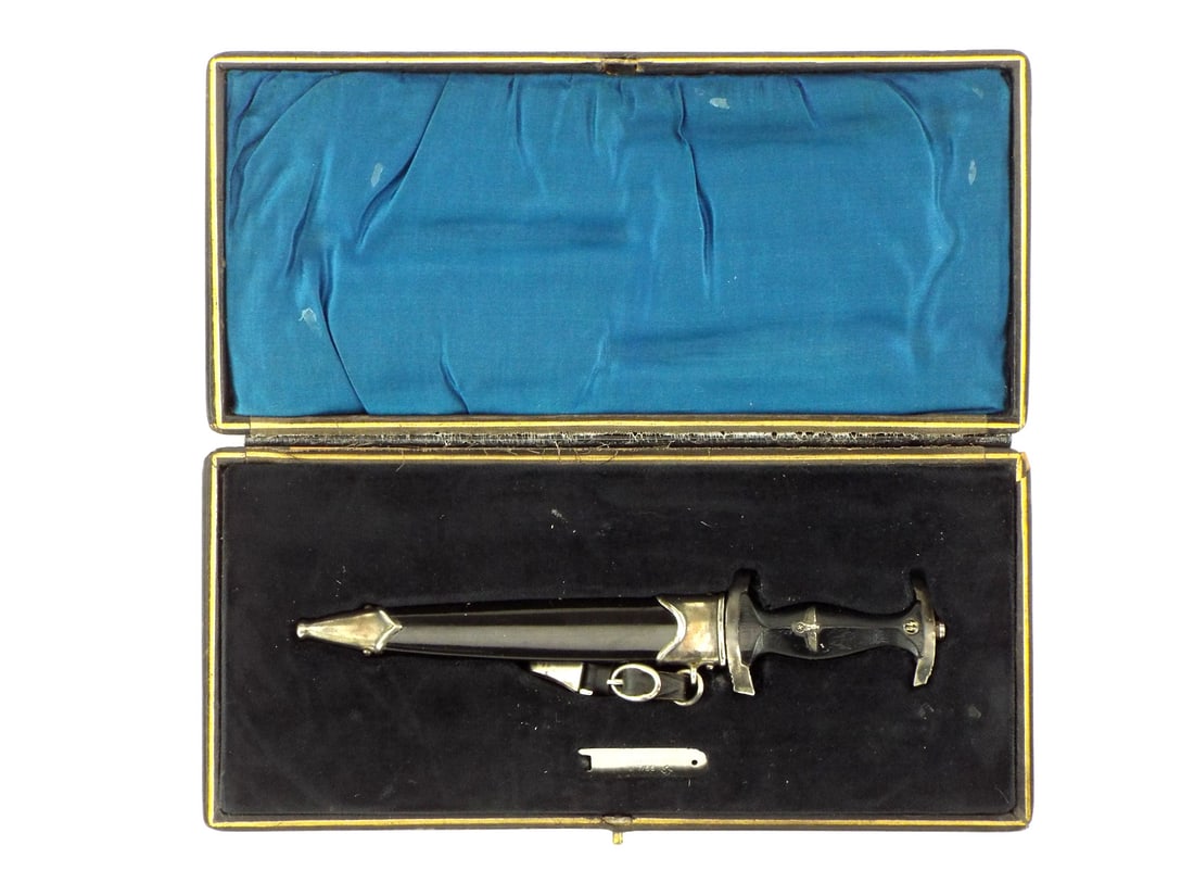 Miniature German SS Honor Dagger in Presentation Box: German miniature SS honor dagger boasting double edged blade engraved with the SS motto "Meine Ehre heißt Treue" ("My honor is loyalty") and RZM circle code M7/13. The black hardwood grip features em