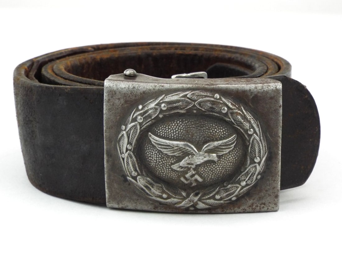 German WWII Luftwaffe Belt & Buckle Stamped Steel & Brown Leather: Combat worn body displays a stamped steel buckle featuring a second pattern flying eagle within a laurel wreath, exhibiting a mellowed patina. The robust brown leather remains supple, retaining its ad
