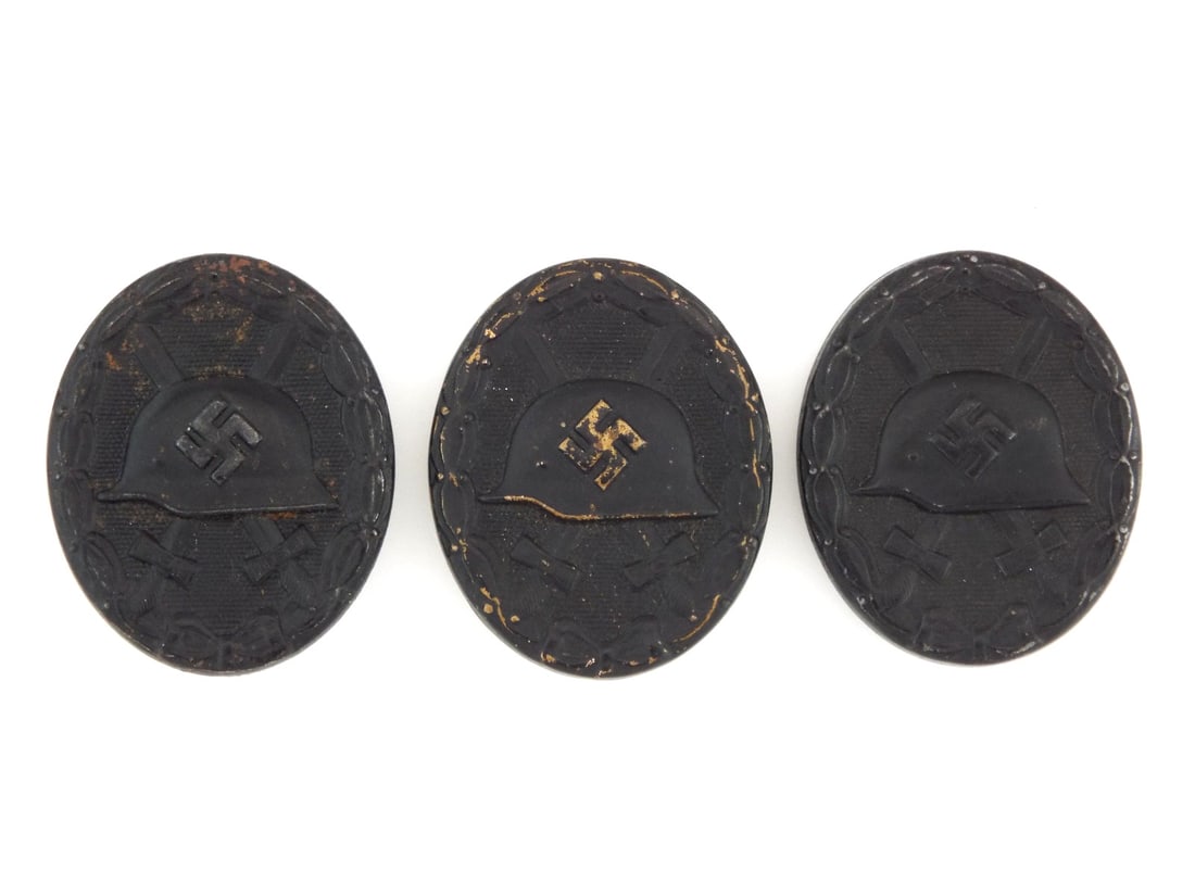 3 German WWII Wound Badges Die Struck Black Grade: 3 black grade awards exhibits a typical hollow back architecture featuring the iconic M35 stahlhelm motif centered over crossed gladii within a crisp laurel wreath. The obverse displays varied stages