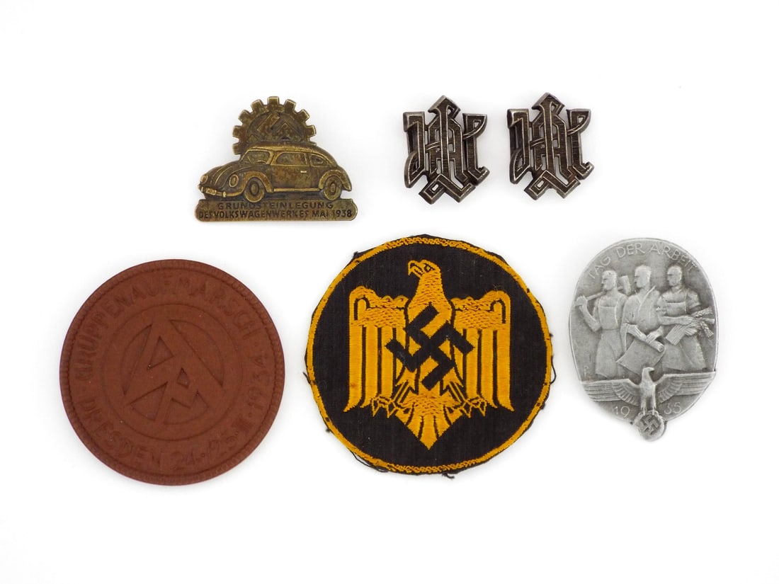 German WWII Ensemble of Tinnies and Pins: Diverse ideological ensemble features a bronze struck 1938 Volkswagen foundation pin displaying a crisp gear and cog motif, alongside a silvered 1935 Tag der Arbeit tinnie exhibiting minor oxidation.