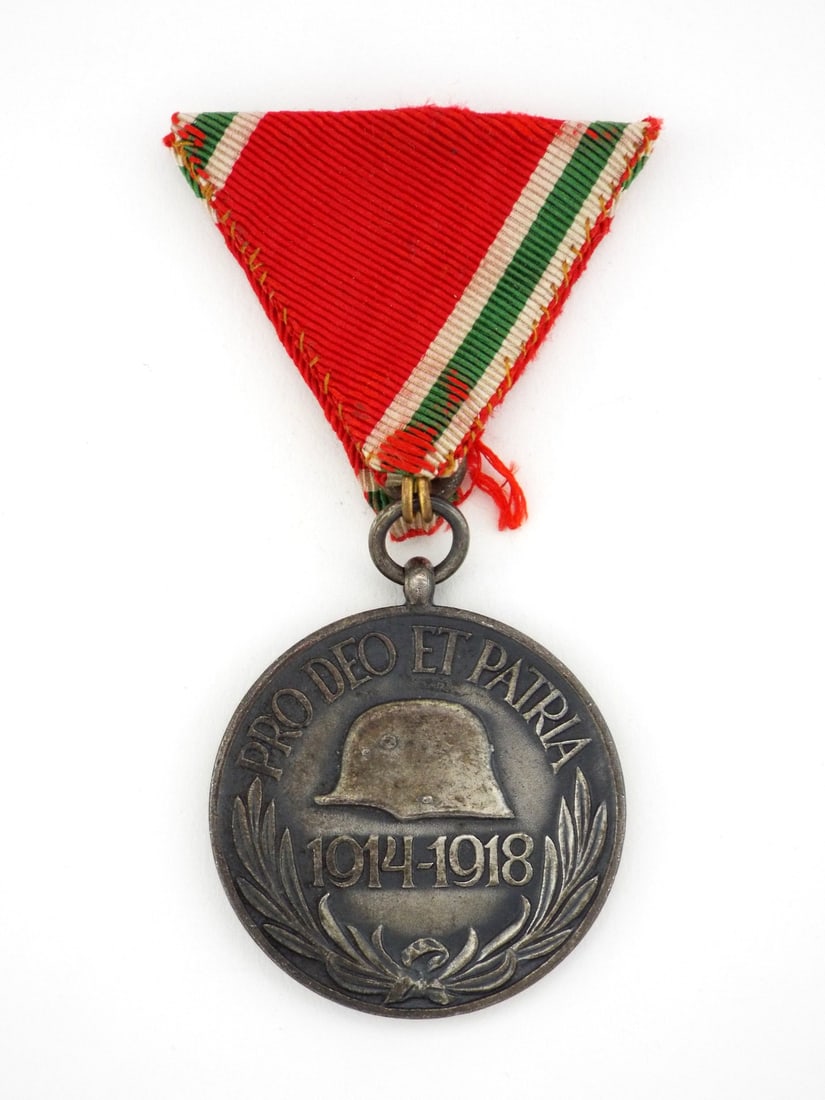 Hungarian WWI COMBATANT COMMEMORATIVE MEDAL: Silvered zinc medal displaying a charcoal patina with high point wear on the central Stahlhelm and 1914-1918 numerals. Obverse features the Hungarian Coat of Arms over crossed swords with moderate oxi