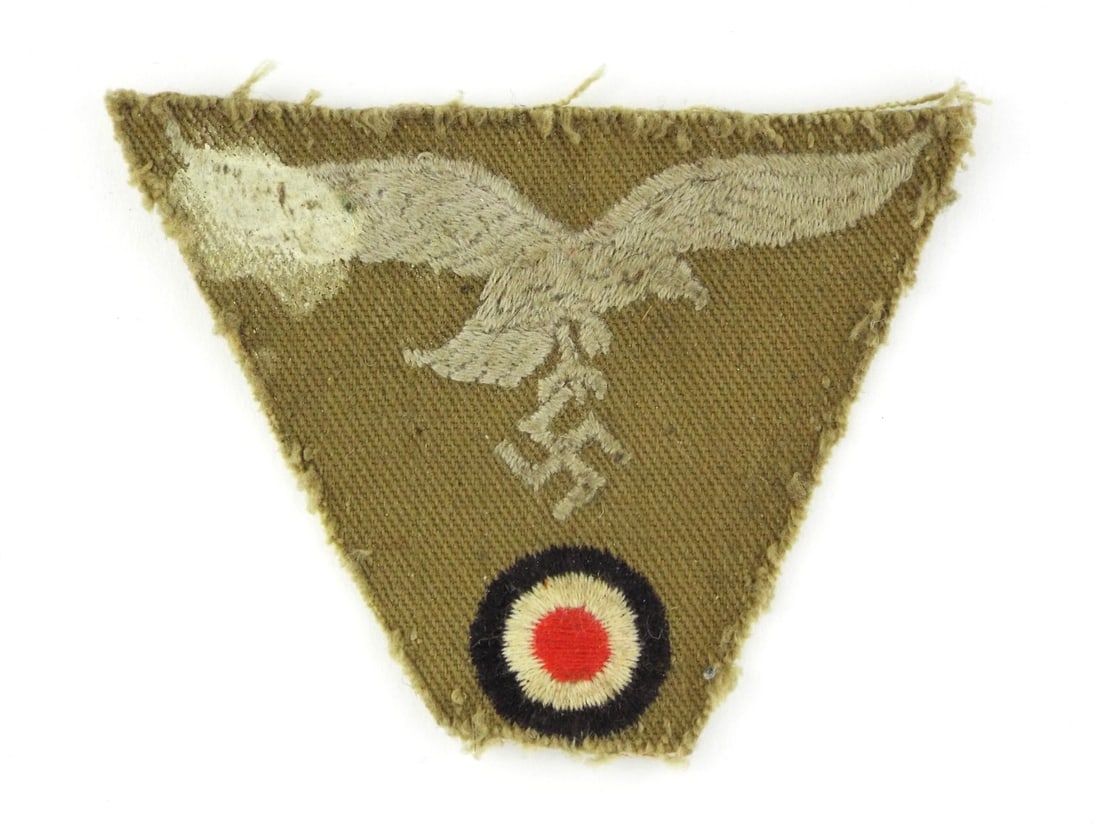 German WWII Afrika Korps LUFTWAFFE Insignia Bevo Woven Tan Twill: Trapezoidal example exhibits a distinctive tan cotton twill body characteristic of Mediterranean theater issue. The integrated Hoheitszeichen and national cockade display significant field wear and ho