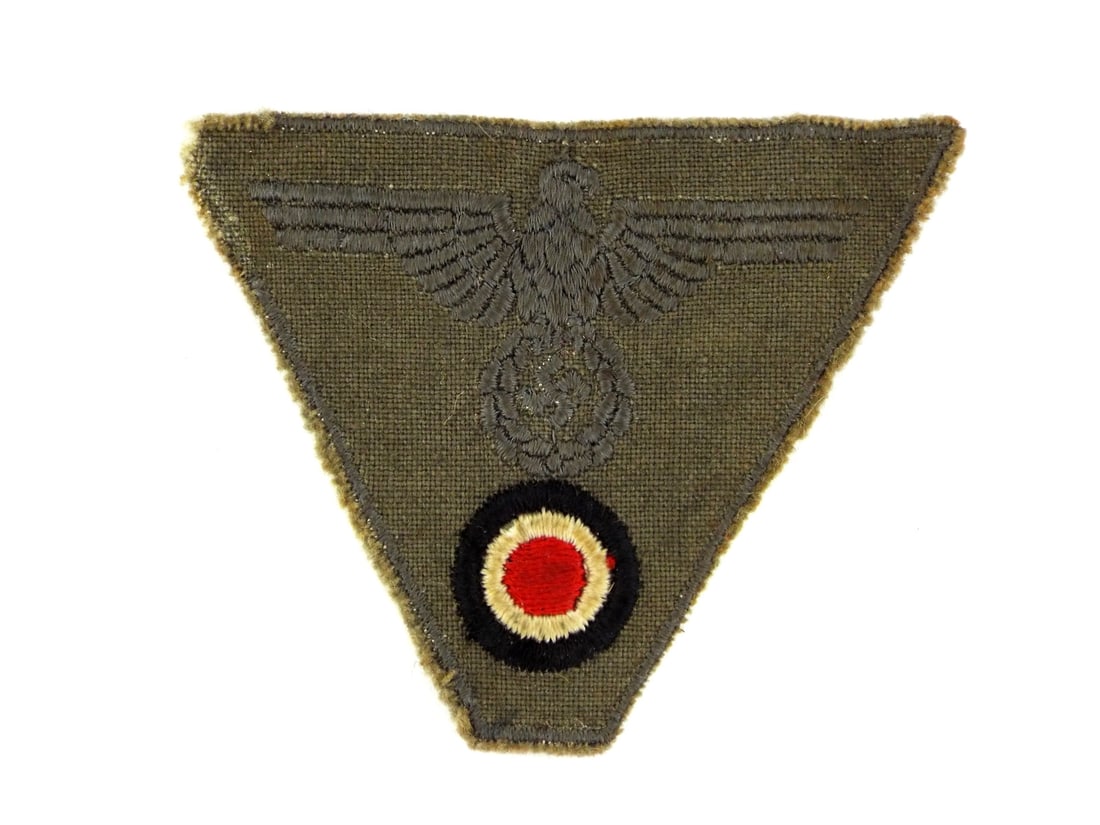 German WWII M43 Afrika Korps FIELD CAP INSIGNIA Bevo Woven Trapezoid: Trapezoid featuring a subdued field grey eagle clutching a wreathed ensign positioned above a tri color national cockade. The BeVo style weave remains tight with crisp definition across the breast and