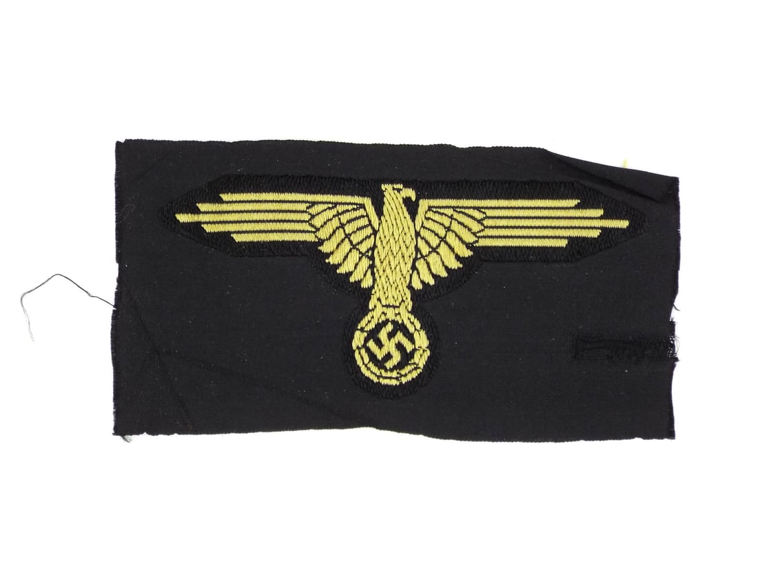 German WWII SS SLEEVE EAGLE RZM Tag & Gold Bullion Embroidery: Embroidered body exhibits tight, lustrous golden thread work atop a dense black silk ground. The characteristic angular wingspan remains crisp with minimal fraying to the raw cut edges. The reverse di