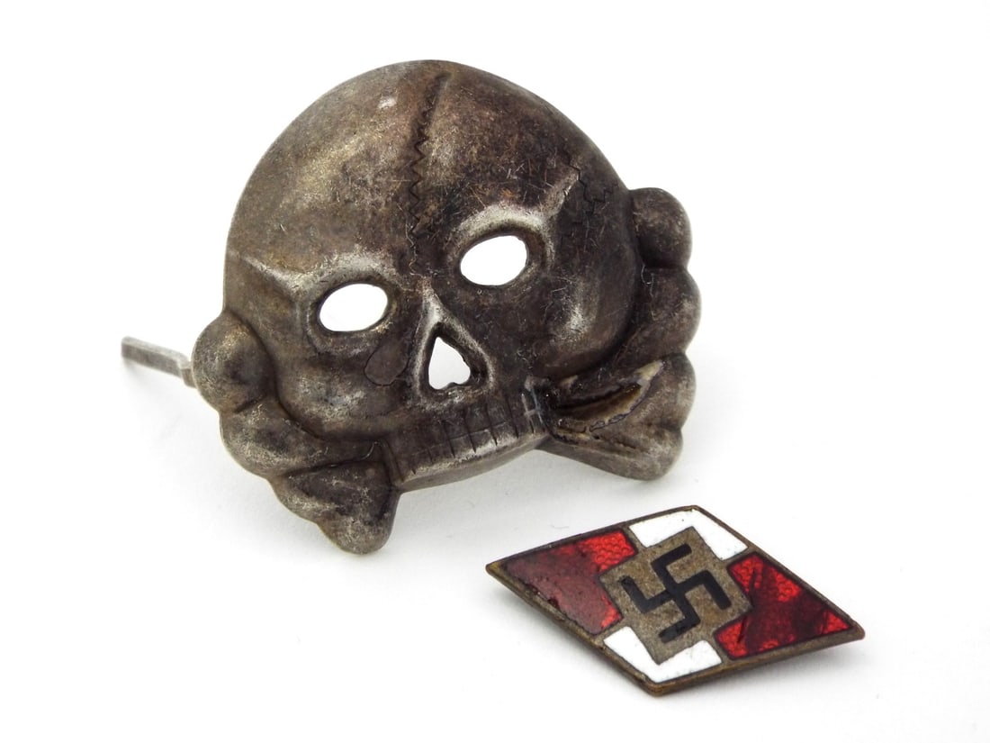 German WWII SS CAP SKULL & HJ BADGE: Silvered cupal SS pattern skull exhibits attic patina, both attachment prongs remain intact and firm. Struck HJ membership diamond shows light surface scratching to the translucent red and opaque whit