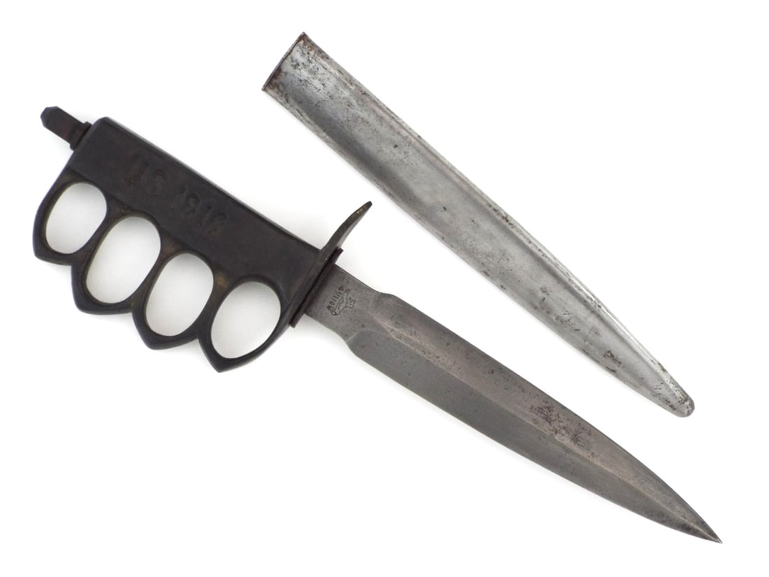 Very Good Copy of 1918 Trench knife: Formidable double edged stiletto blade exhibits a muted charcoal patina and service wear, prominently featuring the AU LION recasso stamp translating to At the Lion. The ergonomic hilt is a casting of