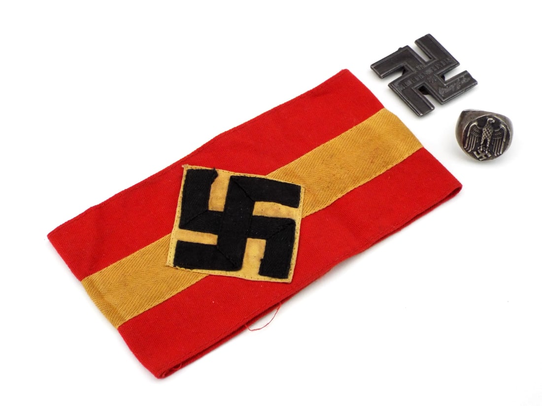 German POST WWII Collection Includes SS SERVICE MEDAL RING & ARMBAND: Lot consisting of POST WWII commemorative items. Red cotton HJ armband with minor fraying. SS Long Service Award displays a matte grey patina, bears a facsimile signature. Signet ring with moderate su