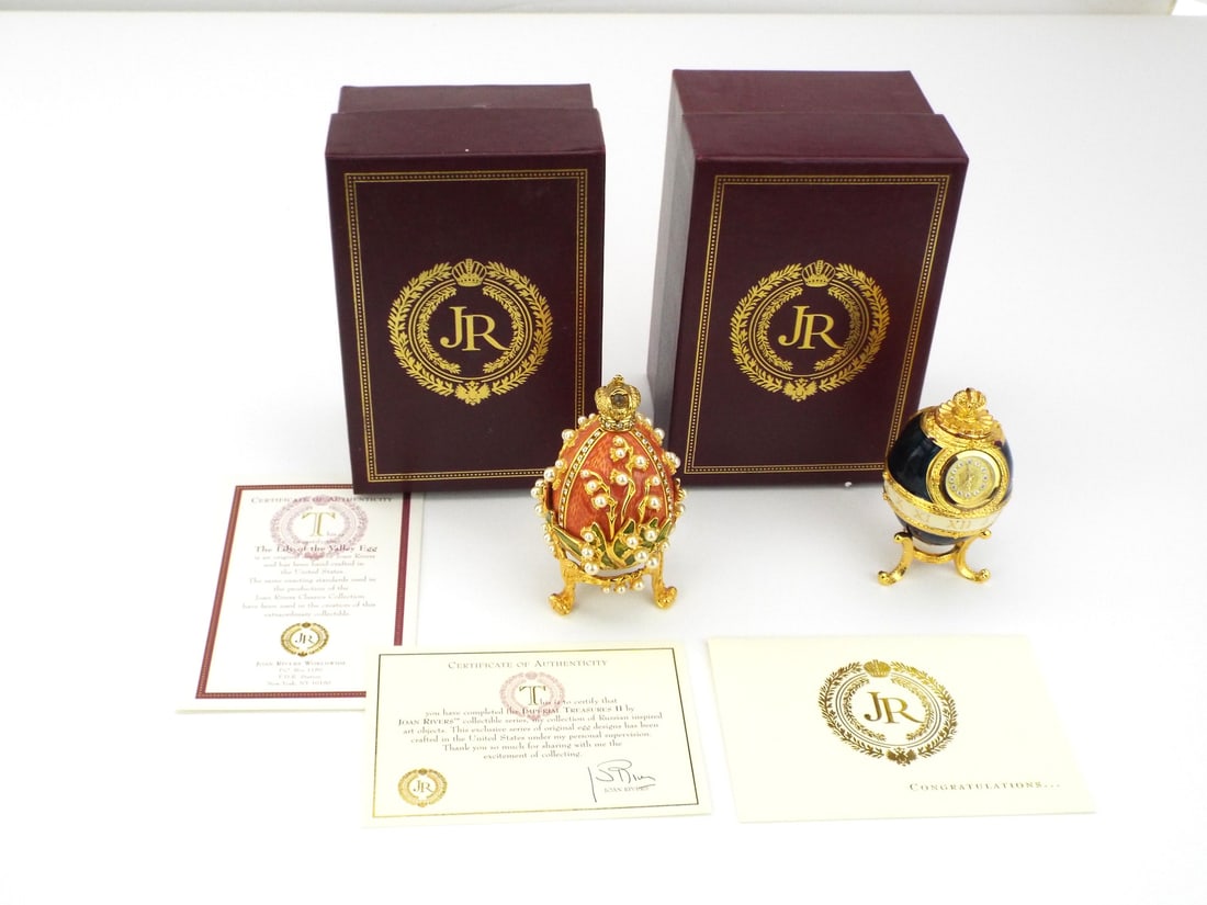 Pair of Imperial Treasures JOAN RIVERS Lily of the Valley & Clock Eggs: Pair of enamel bodies exhibiting salmon and cobalt finishes with inset crystals and faux pearls, Lily of the Valley example features articulated green enamel foliage while Clock piece displays an
