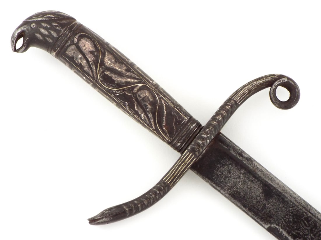 FINE SPANISH/MEXICAN SWORD Silver Niello Work: Spanish or Mexican colonial sword with single edged blade featuring wide spine and finely etched military trophies amid scrolling foliage, steel displaying deep dark patina. Silver mounts lavishly dec