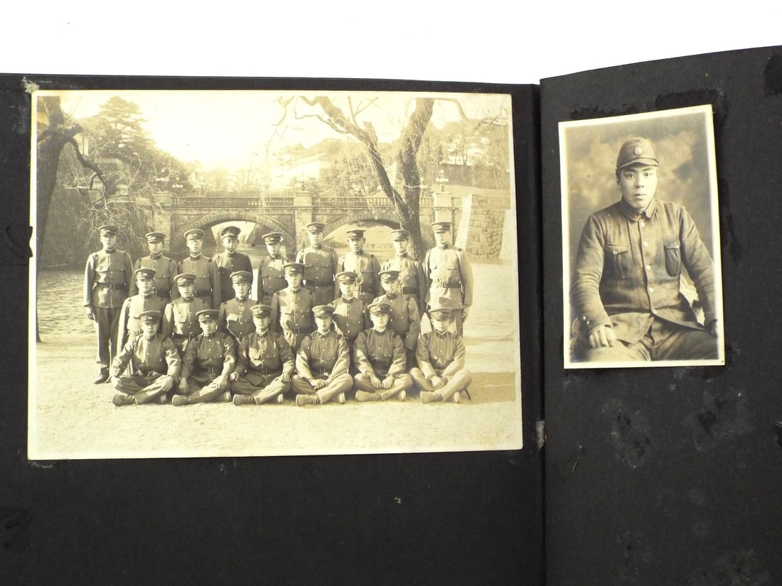 Japanese WWII SOLDIER FAMILY PHOTO ALBUM: Heavily foxed cardstock body bound in textured boards showing significant water staining and peripheral wear to cover edges. Interior features prints of Imperial Japanese Army personnel in Type 98 uni