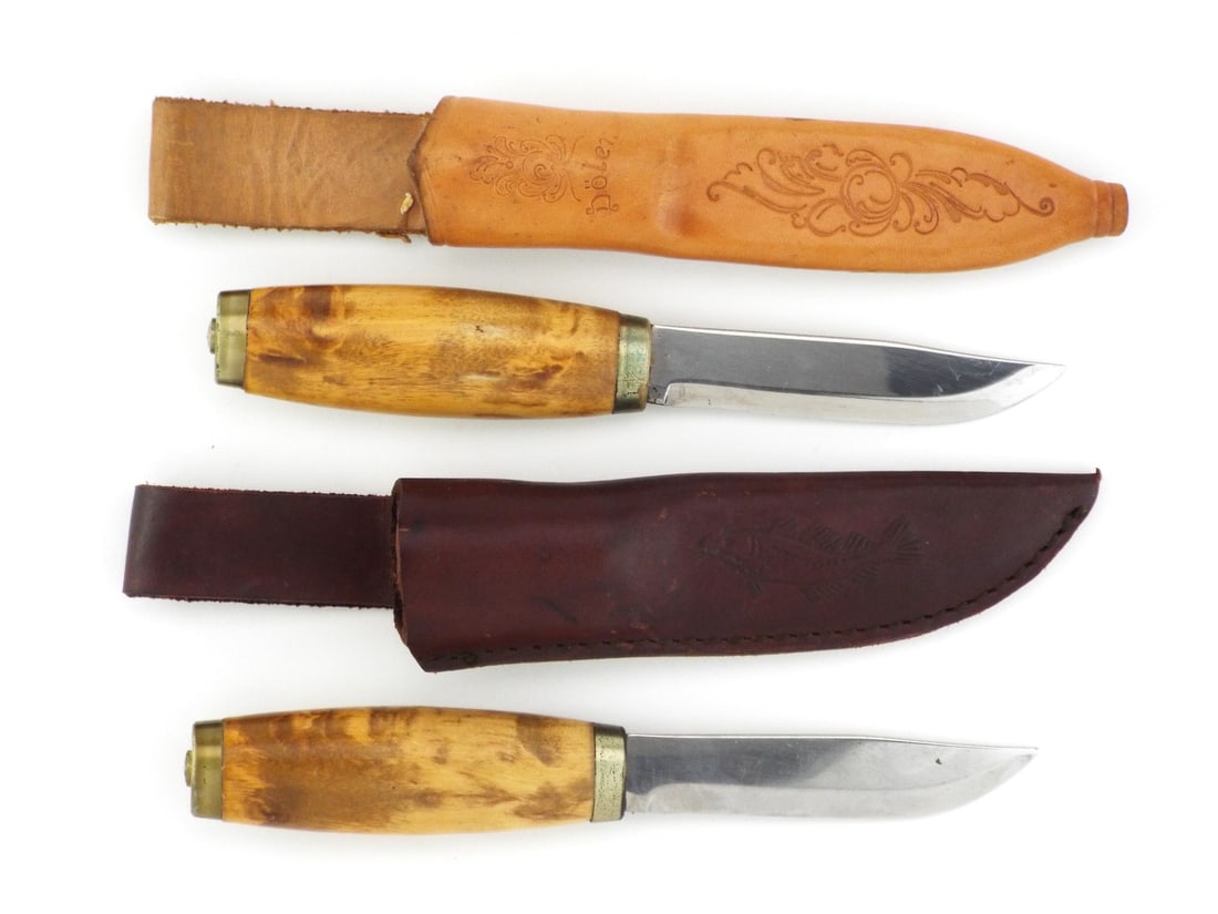 Pair of Norwegian WWII Era PUUKKO KNIVES: Polished stainless steel blades exhibit minor surface scuffing and factory edge retention. Figured curly birch handles show honest hand wear with tight brass bolsters and pommel caps. One cowhide shea