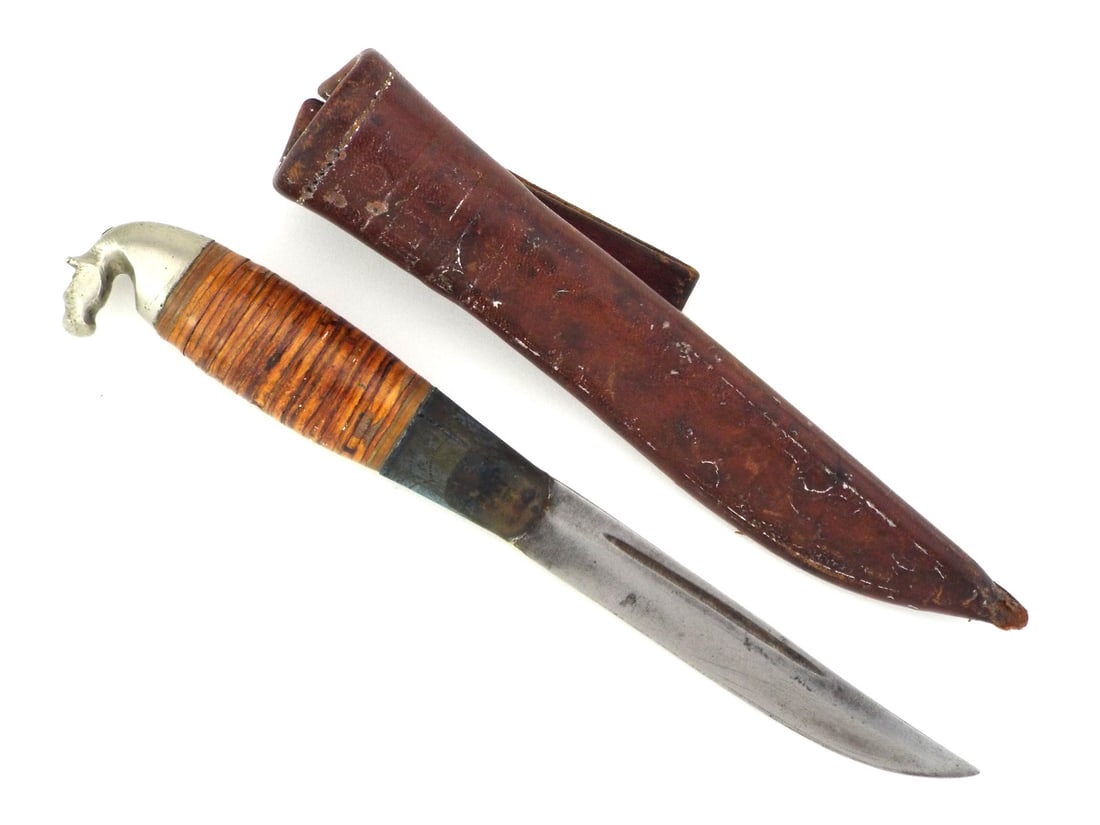 Finnish WWII PUUKKO KNIFE Horse Head Pommel & Birch Handle: Blade showing age toning, localized oxidation and a deep fuller. Hilt features a stacked birch bark grip with a cast metal horse head pommel and an oxidized ferrule displaying faint geometric engravin