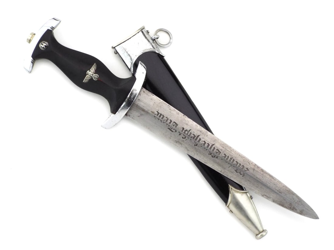 German WWII SS Dagger by CARL EICKHORN with RZM: Blade displays moderate surface oxidation with engraved motto translating to My Honor is Loyalty and RZM 941/39 SS maker mark which relates to Carl Eickhorn. Black contoured wood grip shows minor hair