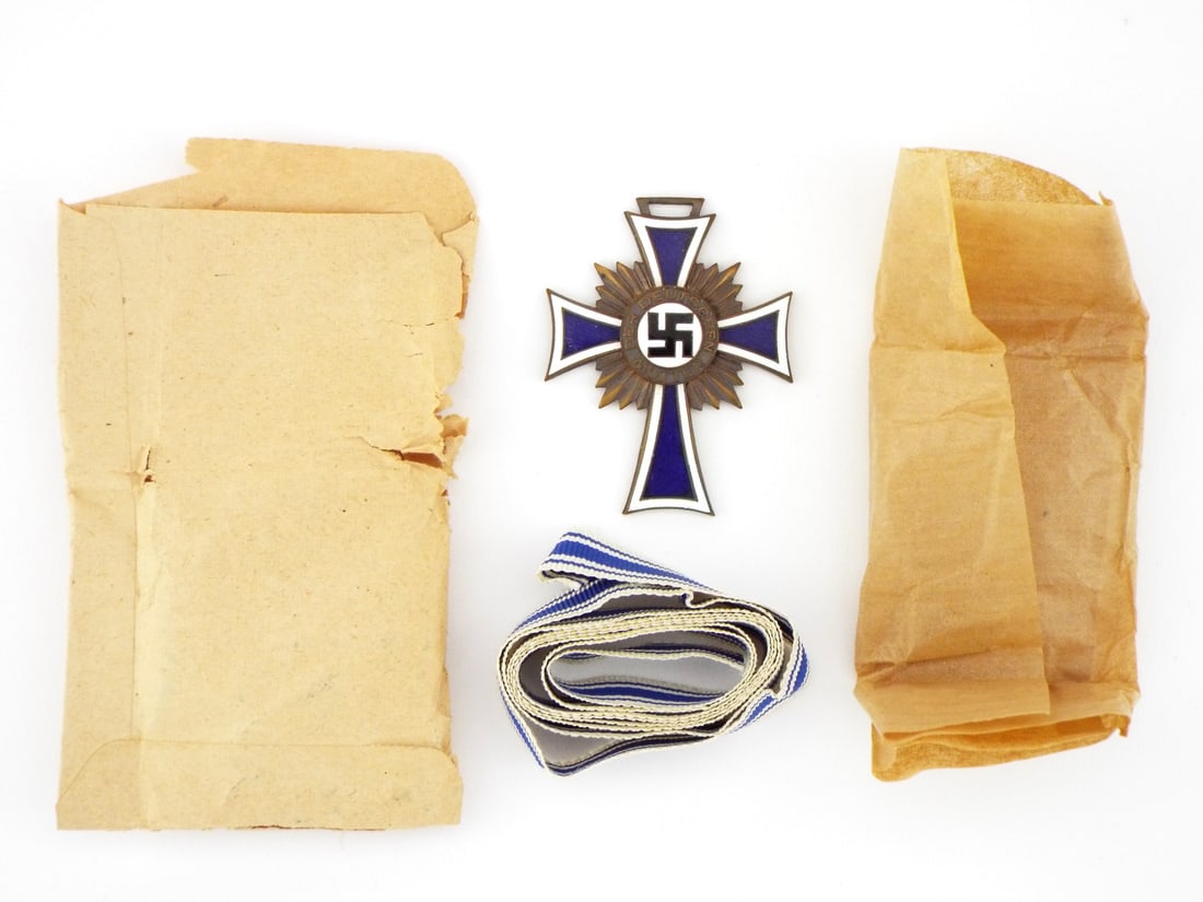 German WWII Complete Unissued Bronze Mothers Cross Medal: Fresh from a recent estate find we are able to offer this unissued example of a full size German Mother's Cross complete with it's shipping packet, packing tissue, and full length of neck ribbon. Such