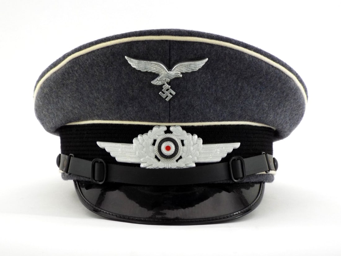 Very Good Quality German Made POST WWII Herman Goring Division Officer Visor Cap: Wool body exhibits white branch piping for elite unit with exceptionally clean nap. Aluminum Luftwaffe eagle and winged cockade mounted to a crisp mohair band. Interior features yellow silken lining w