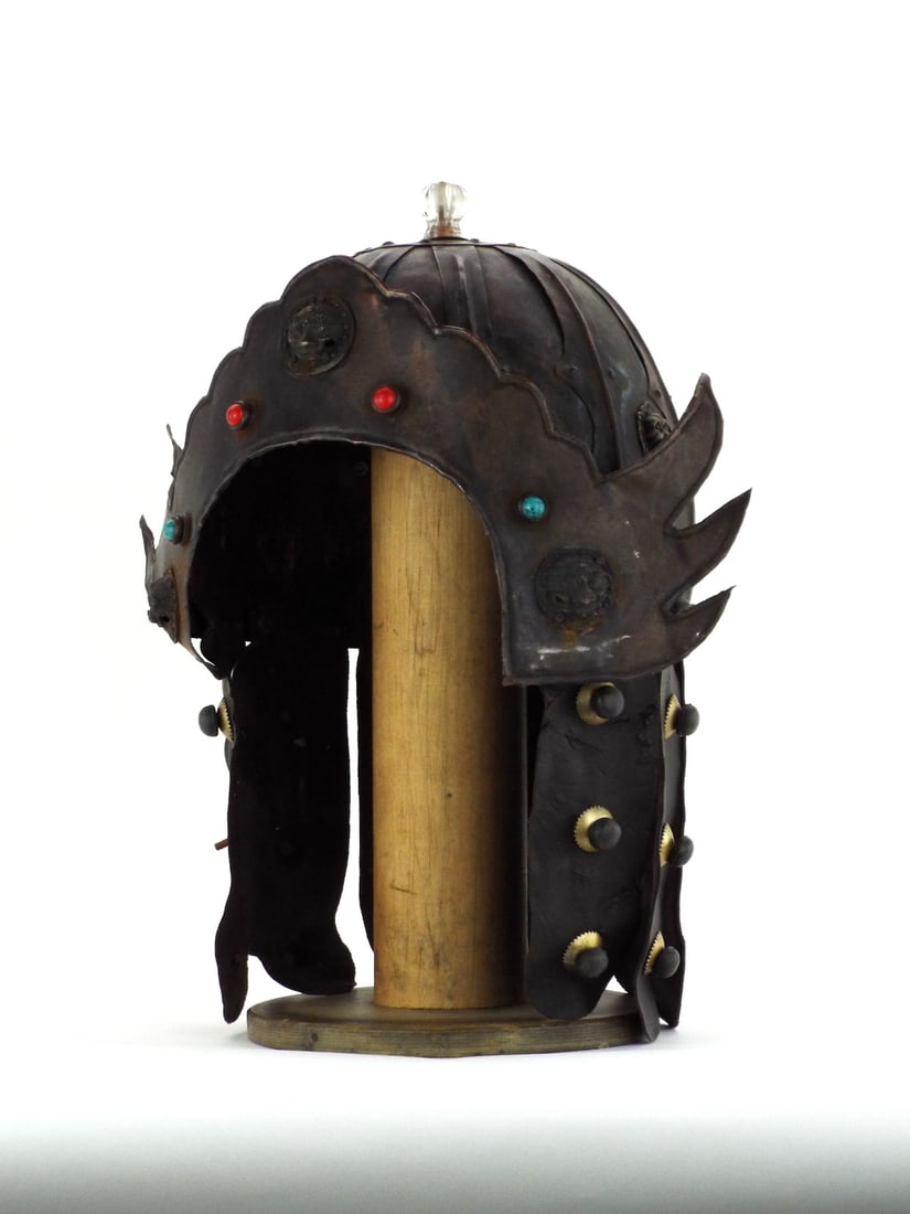 Tibetan Style Helmet Adorned with LION MASCARONS & CABOCHONS: Sheet metal skull of segmented construction exhibits heavy oxidation and patination throughout. Brow plate features tiered scalloped edges set with glass cabochons and applied brass lion head mounts. 