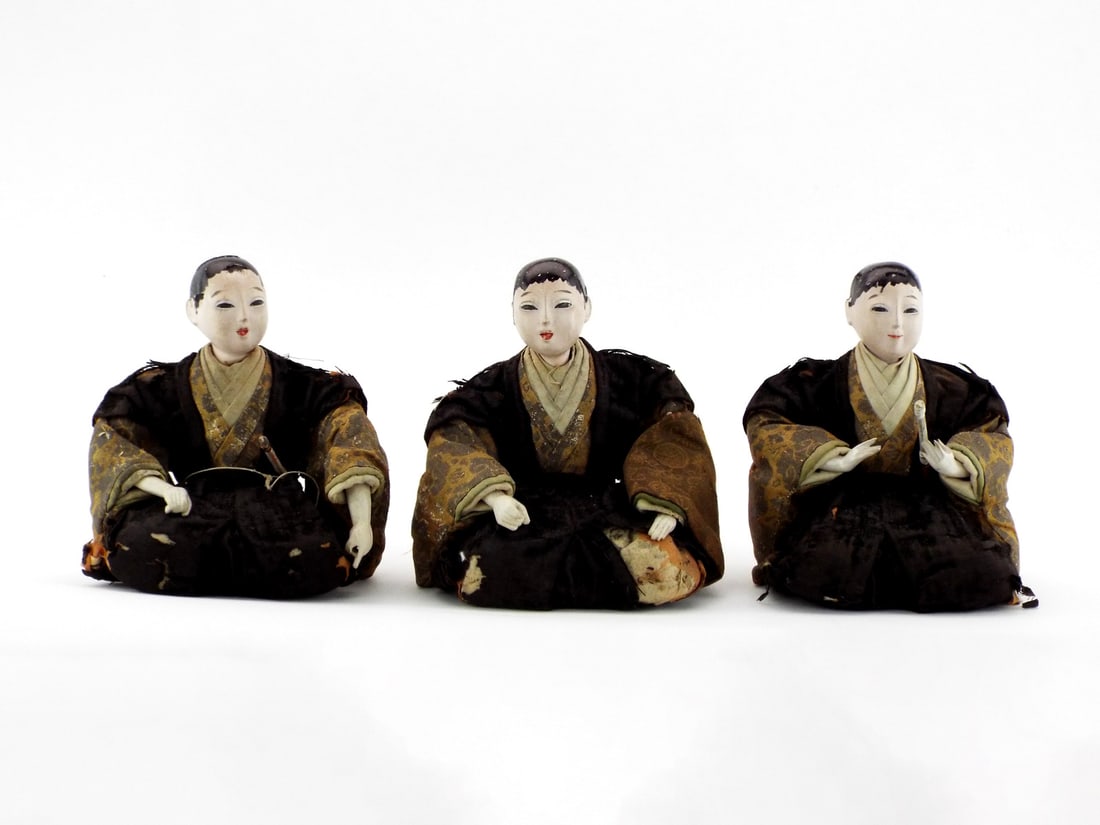 Trio of Japanese Ido Period Samurai Dolls BROCADE TEXTILES: Silk wrapped straw forms show extensive fraying to the black formal vests and patterned sleeves. The white oyster shell pigment faces exhibit stable crazing, surface soil and scattered loss to the bla