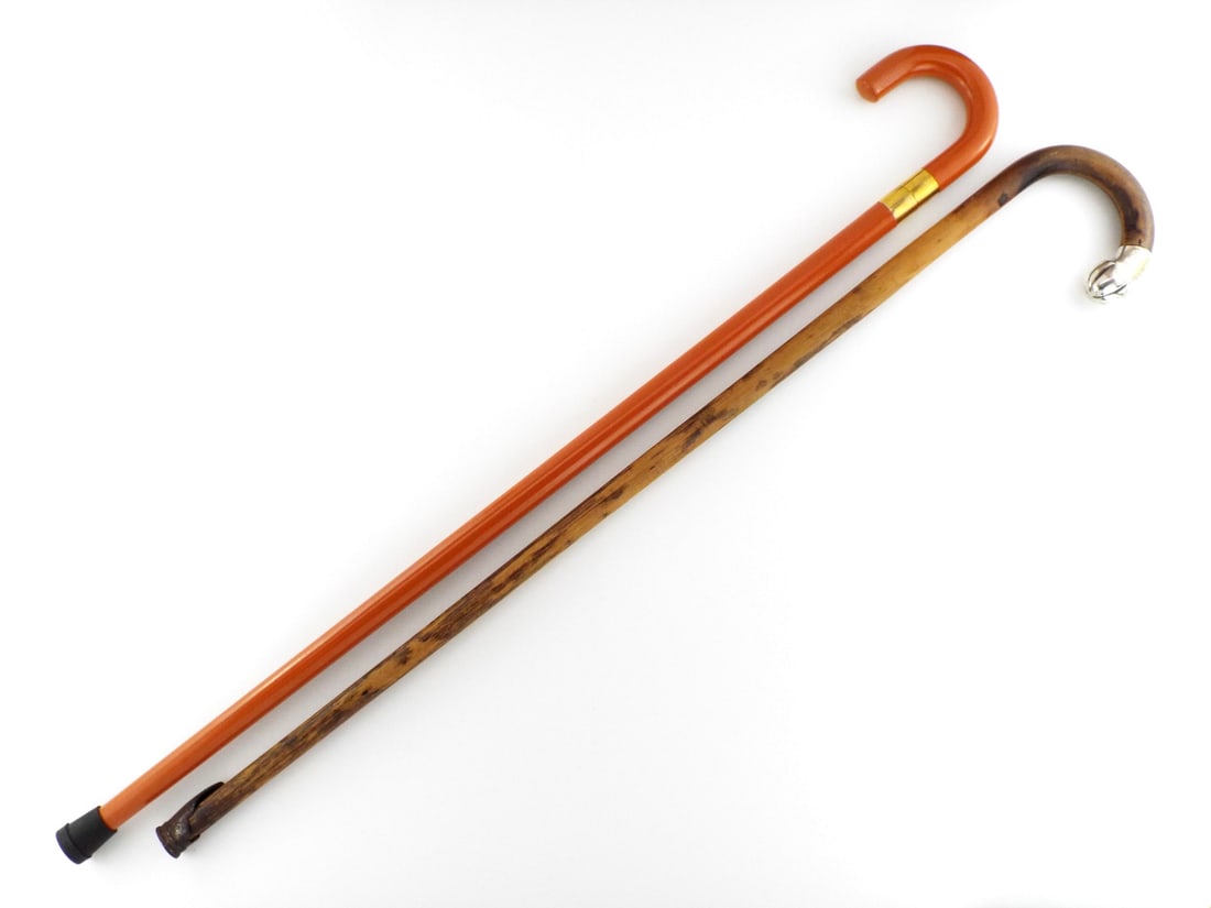 Lot of Walking Cane & Cane Sword: Lot of two walking canes. The first features a square section thrusting sword blade housed within an orange body secured by a threaded brass collar, showing minimal wear. The second cane consists of a