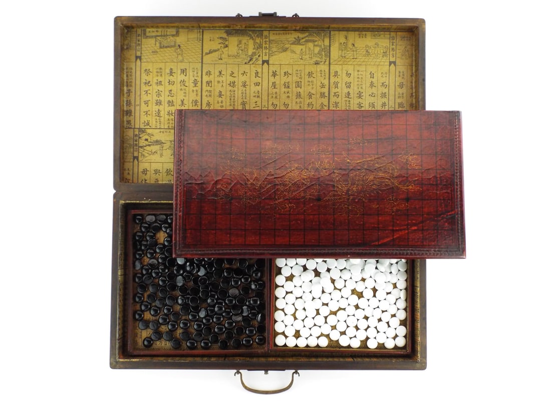 Antique Chinese Game Board with GILT DRAGON PHOENIX Decoration: Composition stones exhibit smooth surfaces without fractures housed in twin paper lined wooden trays showing light shelf wear. Interior case walls lined with printed almanac paper showing minor foxing