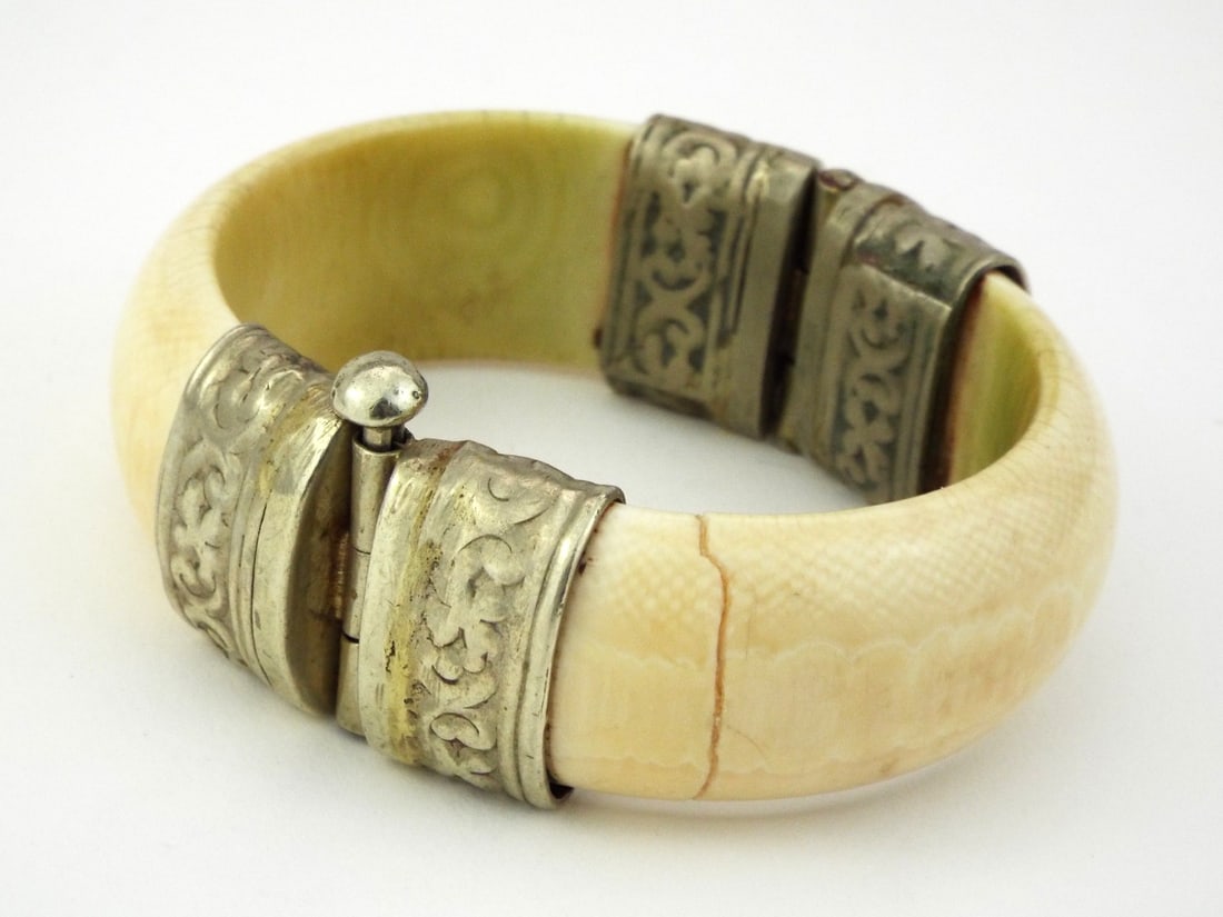 Very Fine Anglo-Indian 19th C. HINGED CUFF with Repousse Silver Mounts: Very Fine curved paired sections displaying prominent Schreger lines and a mellowed cream patina, one section exhibits a vertical age related stress crack. Foliate scroll repousse silver mounts secure