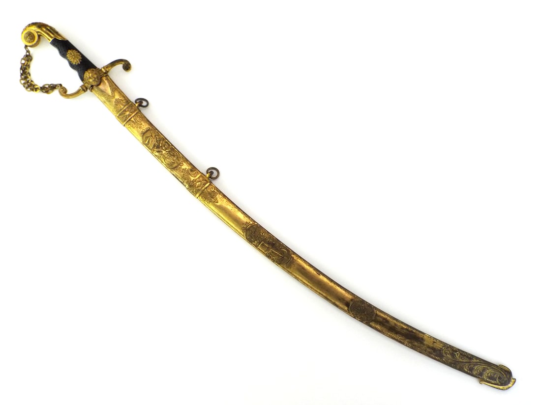 French Napoleonic Wars General Sword GILT BRASS & EBONY GRIP: Curved steel blade displays localized spotting and heavy oxidation near the ricasso. Ebonized wood grip features carved scale motif and central brass rosette, showing minor age cracking. Gilt brass hi