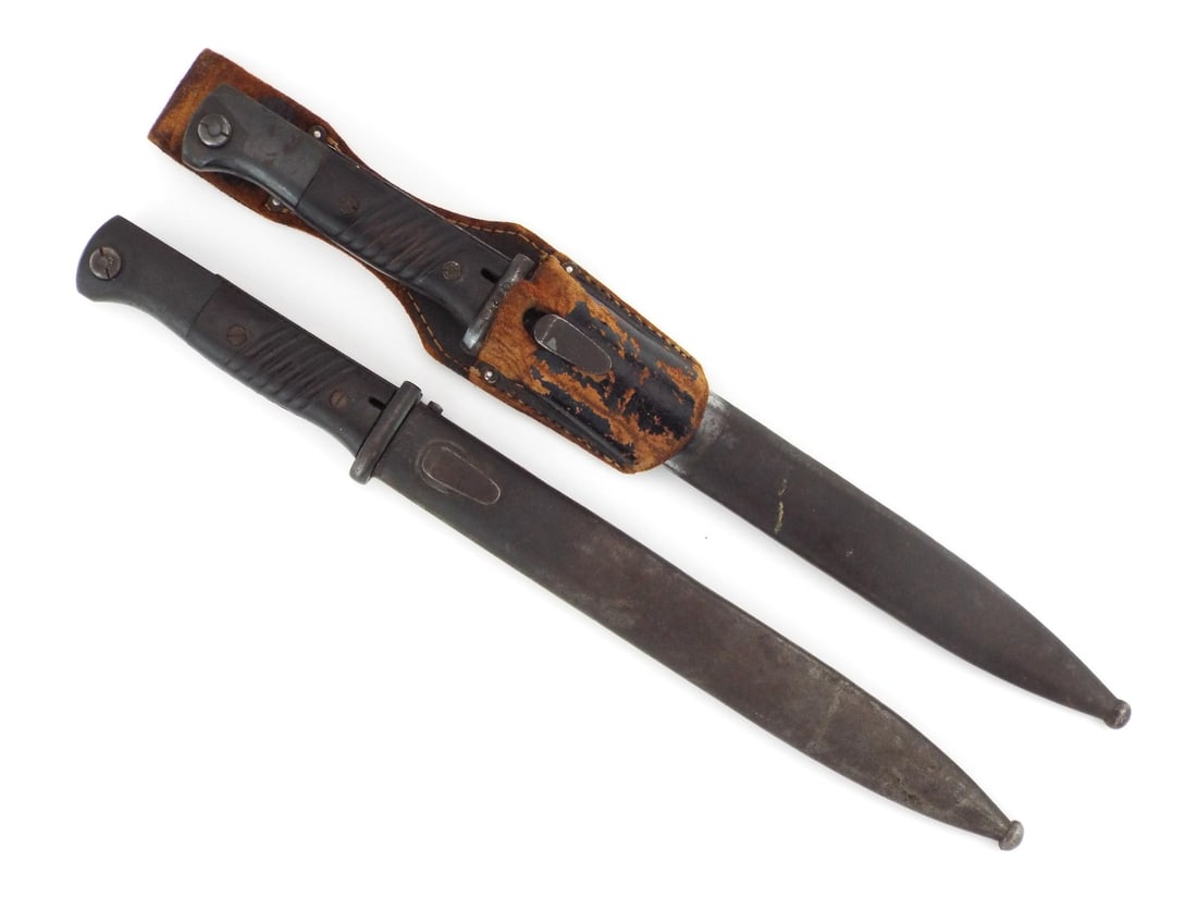 Two German WWII K98 Bayonets: Pair of combat bayonets, one Horster blade retains strong bluing with serial 7079c, while the AWS Alcoso blade shows heavy sharpening wear and gray patina. Both feature ribbed black Bakelite grips, on