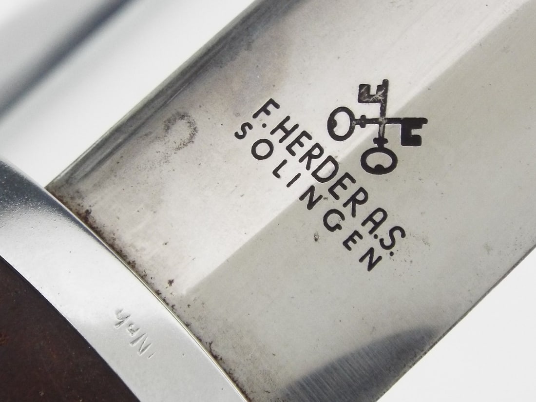 German WWII SA Dagger By F. HERDER A.S. SOLINGEN with Nickel Fittings: Bright double edged blade displays the acid etched motto translated as All for Germany with crisp maker logo on reverse showing minor runner marks and light superficial scuffs. Solid brown wood hilt s