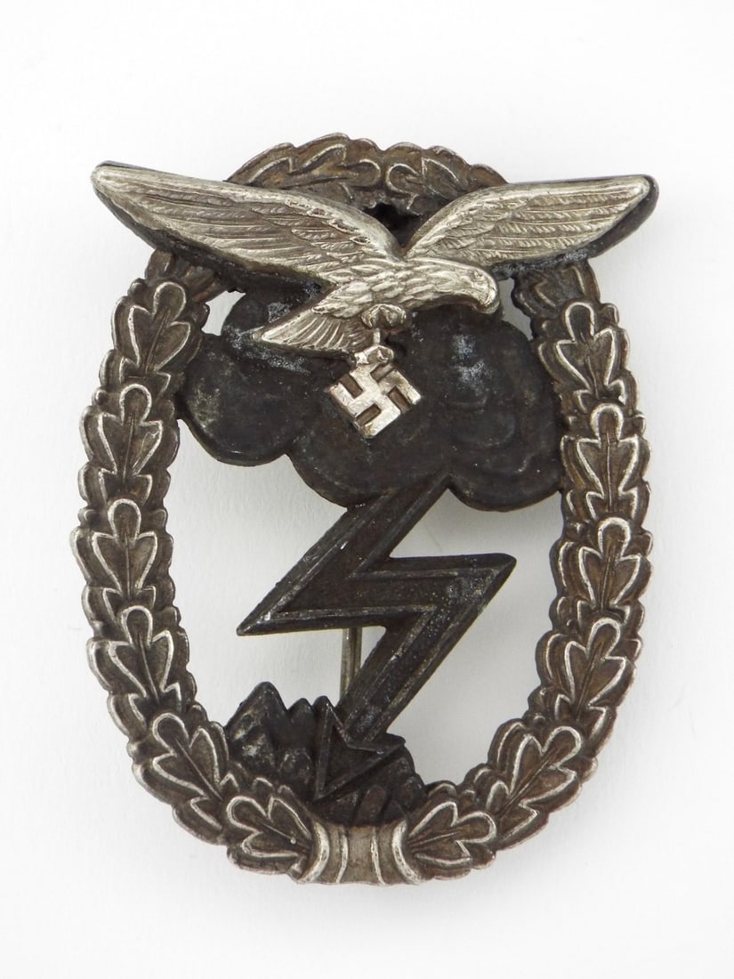 German WWII Luftwaffe Ground Combat Badge By GUSTAV BREHMER Two Piece Construction: German WWII Luftwaffe Ground Combat medal constructed of zinc with a separately riveted nickel silver eagle, featuring a striking lightning bolt and storm cloud motif. The gray metal body shows typica