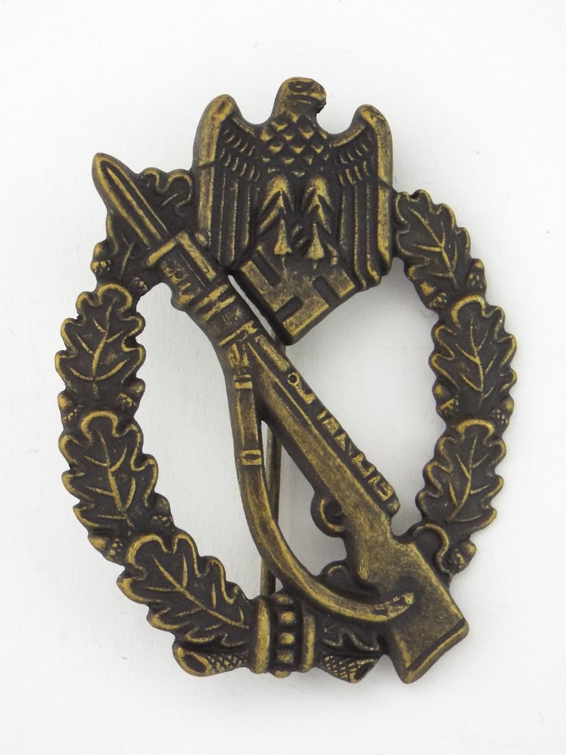 German WWII Infantry Assault Badge By S.H. u. Co. 41: Badge exhibits darkened brass bronze patina over cast metal body. Detail definition on oak leaf wreath, Karabiner 98k rifle and eagle remains soft. Reverse features integral hinge, pin and catch assem