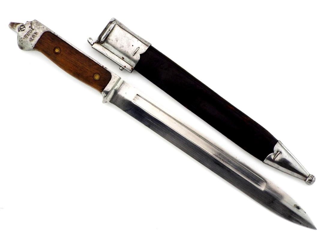 Rare & Excellent Danish WWI-WWII Krag-Jorgensen Bayonet Dagger with Matched Scabbard: Bright single fullered blade shows minimal age toning and crisp arsenal stamp. Walnut grip scales remain solid with light service bruising and correct brass rivets, pommel retains a functioning lock b