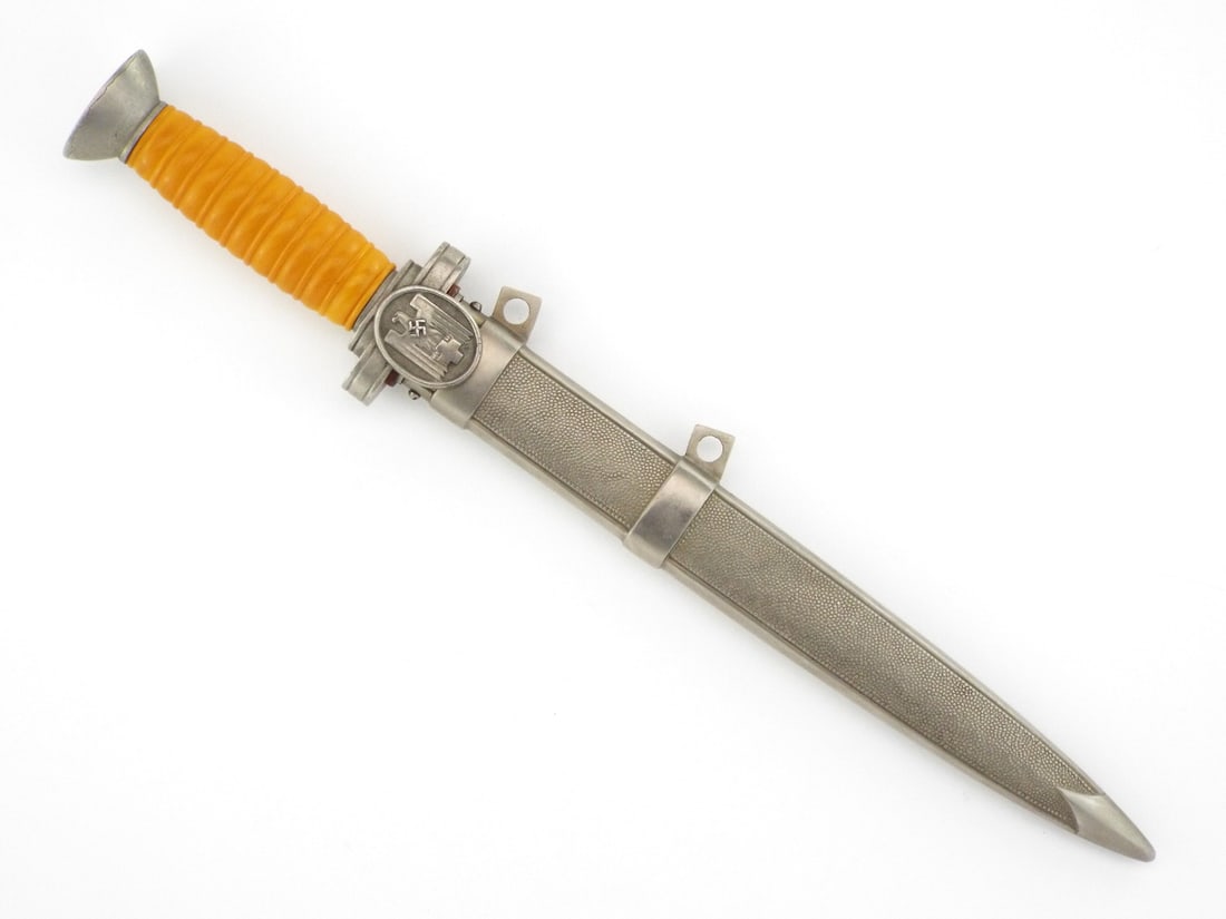 German WWII RED CROSS DRK Leader Dagger with Scabbard: Double edged stiletto blade exhibits graying and surface mottling with standard unmarked ricasso. Molded amber grip remains solid with light wear to the spiral grooves. Conical oak leaf pommel secures