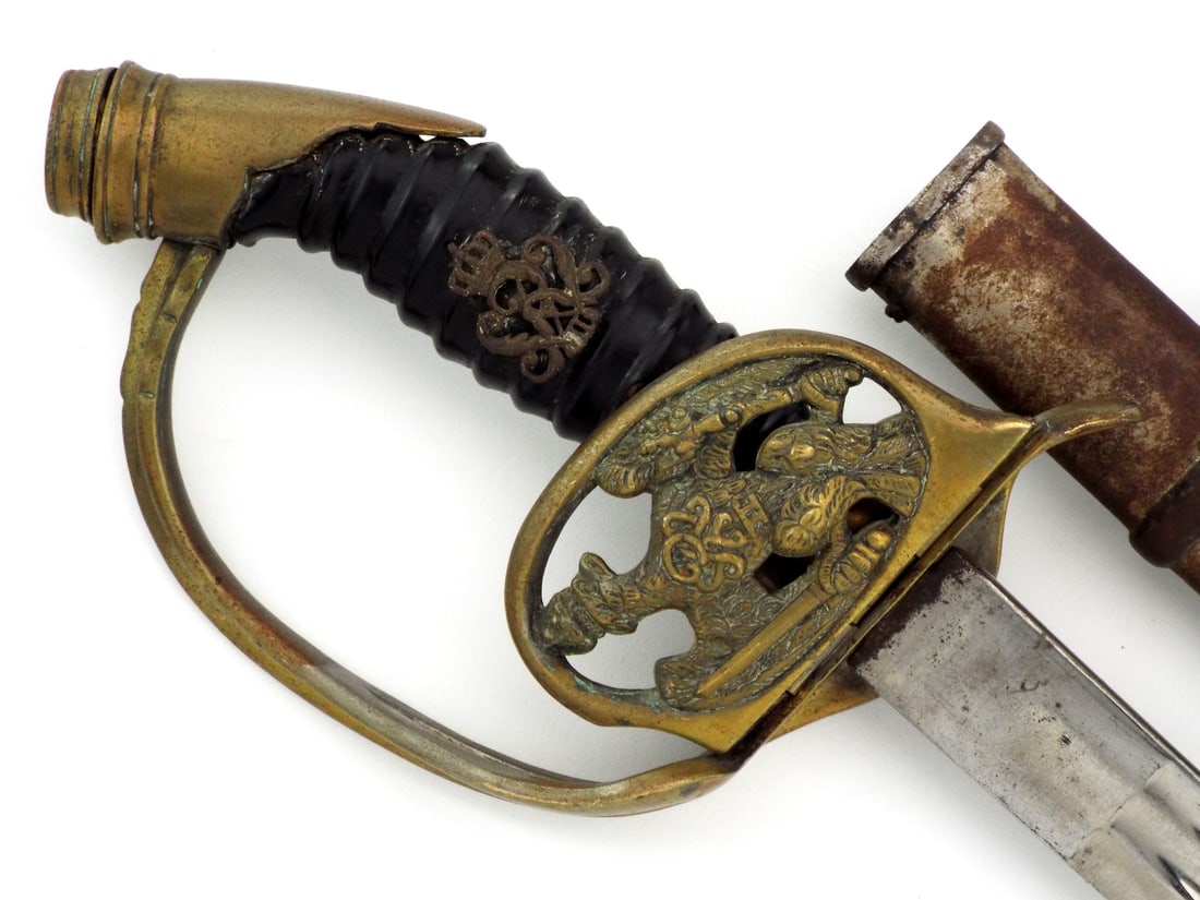 Prussian WWI Infantry Officer Sword By CLEMEN & JUNG with Folding Guard: Straight, nickeled, dual fullered steel blade displays moderate oxidation and spotting near the ricasso with a visible shield and Z maker mark. Brass hilt features a folding counter guard with the cro